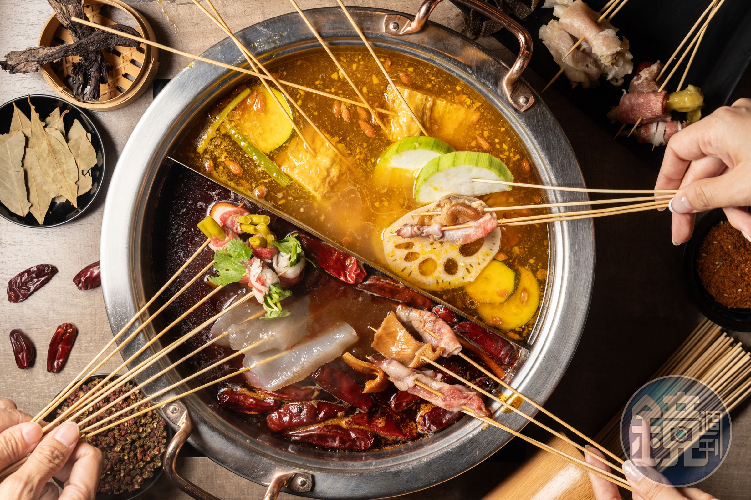 「苗妞串串香麻辣鍋」的鍋底「麻辣豆鼓肉末鍋」（下）與「二星藤椒金湯鍋」（上）皆加入貴州特產木姜子油調味。（380元／鴛鴦鍋任意搭）