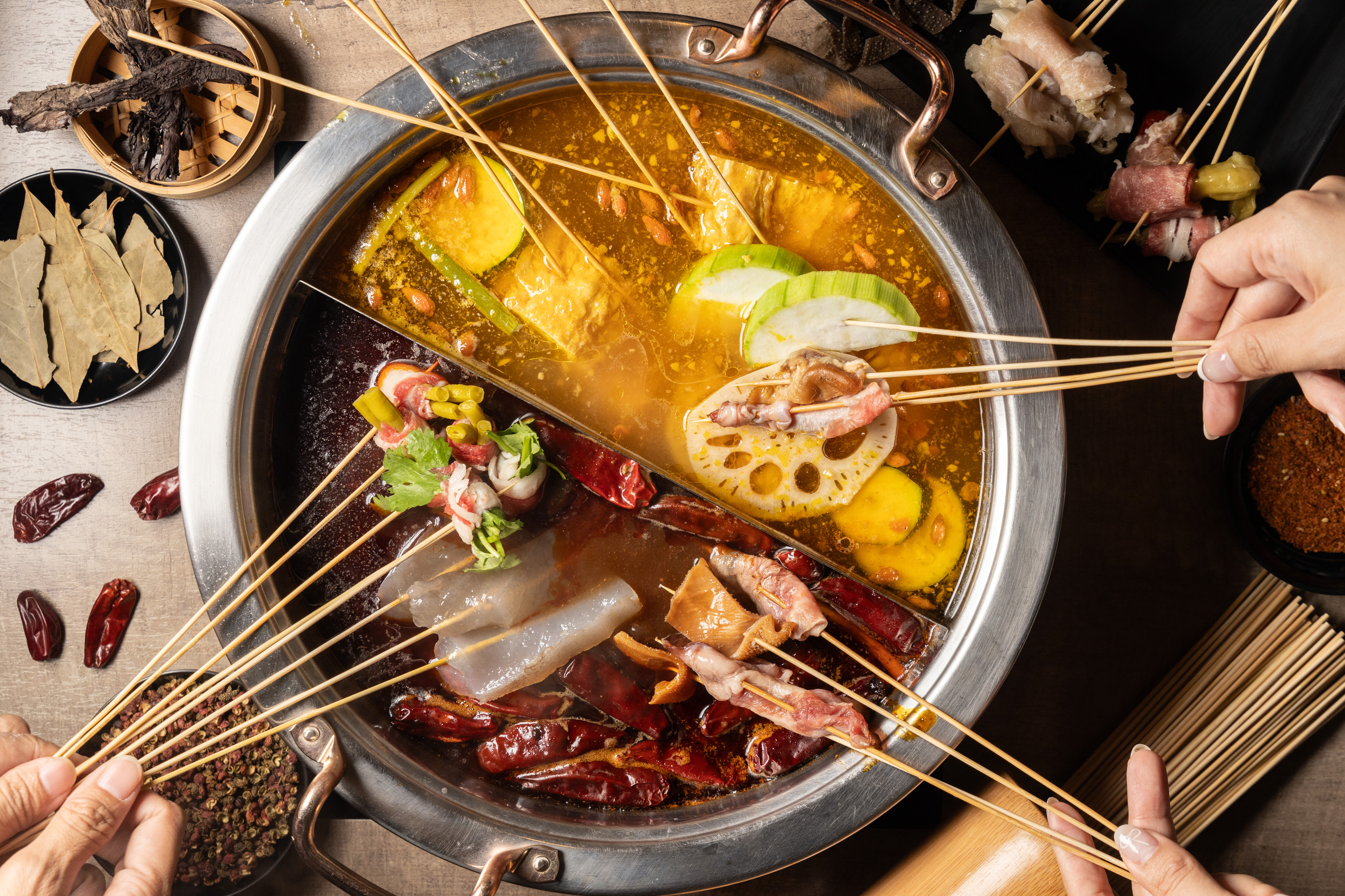 「苗妞串串香麻辣鍋」的鍋底「麻辣豆鼓肉末鍋」（下）與「二星藤椒金湯鍋」（上）皆加入貴州特產木姜子油調味。（380元／鴛鴦鍋任意搭）