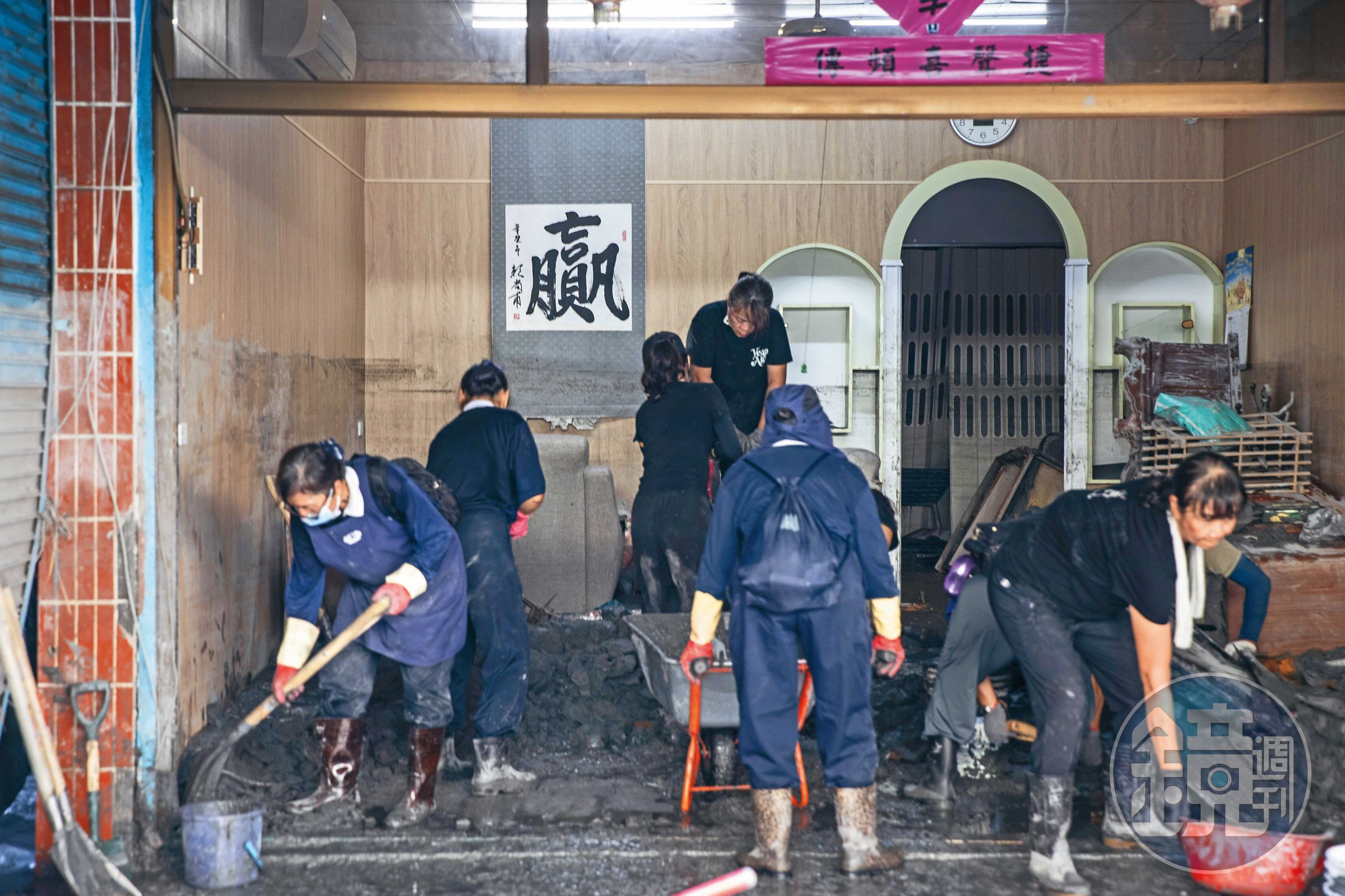慈濟志工進民宅協助清淤,屋內牆上的「贏」字,似在鼓勵災民及為志工加油。