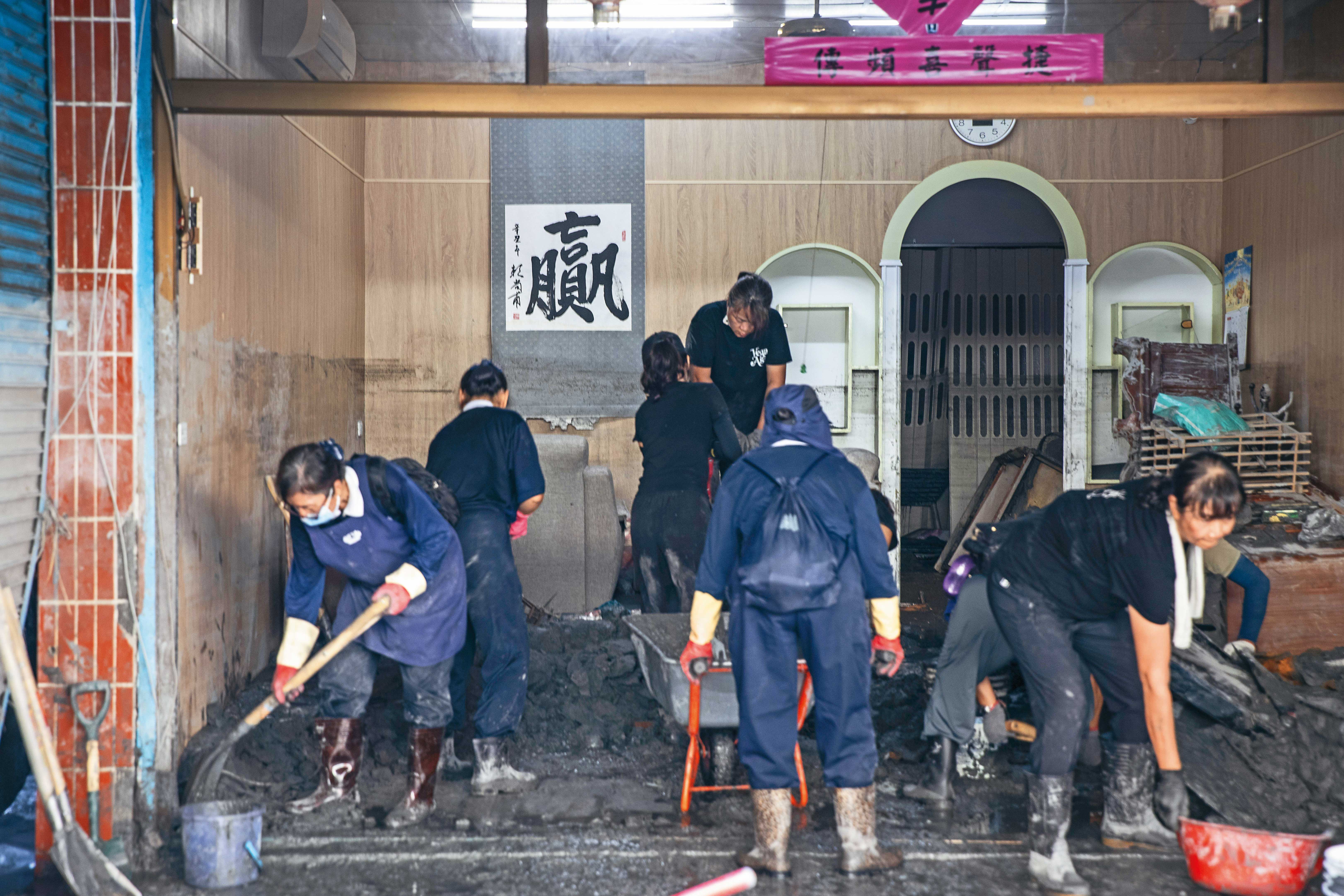 慈濟志工進民宅協助清淤，屋內牆上的「贏」字，似在鼓勵災民及為志工加油。
