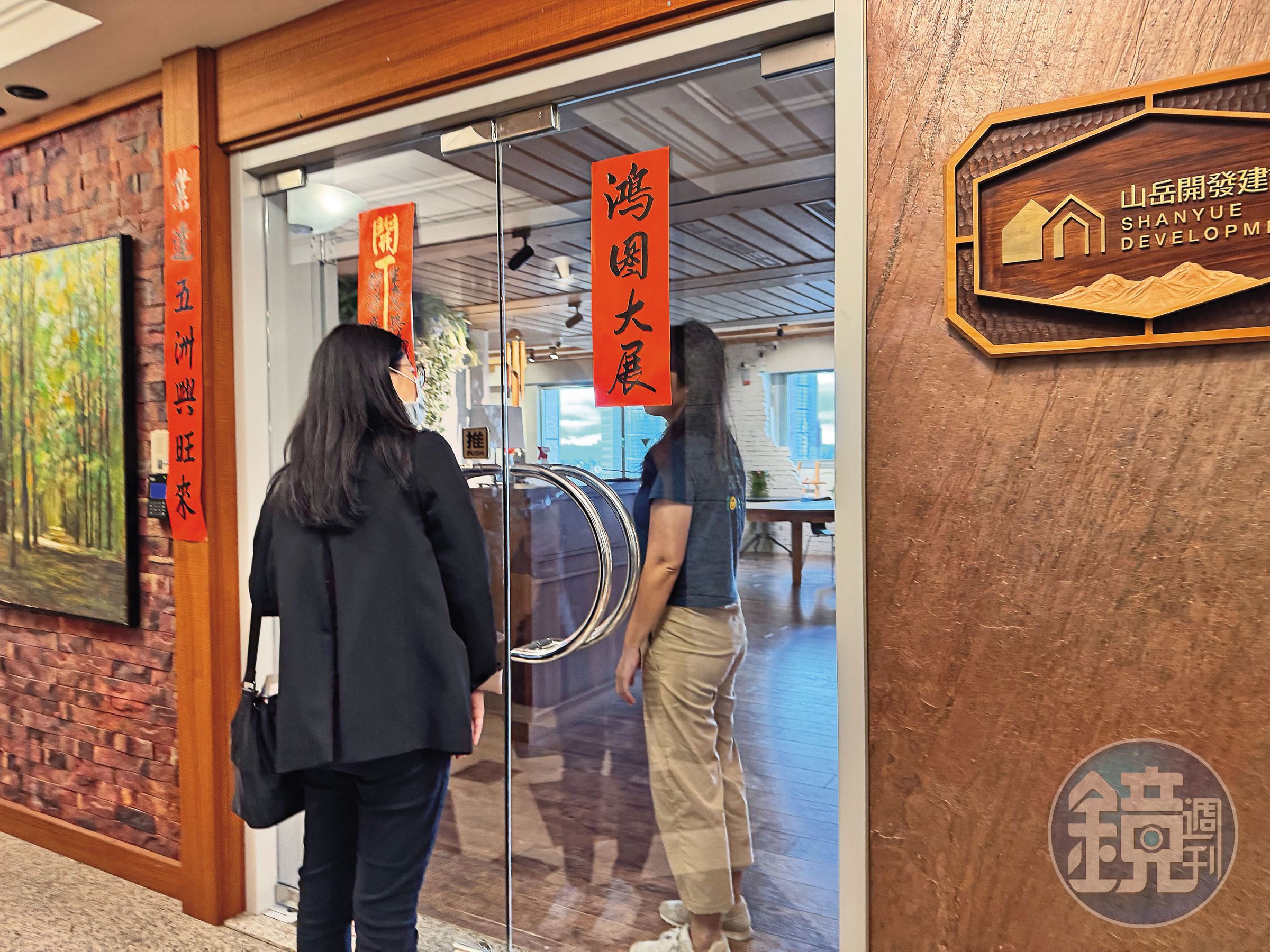 本刊前往山岳建設查證汐止都更爭議,一名女性員工(右)透過上鎖的玻璃門縫隙表示不回應。