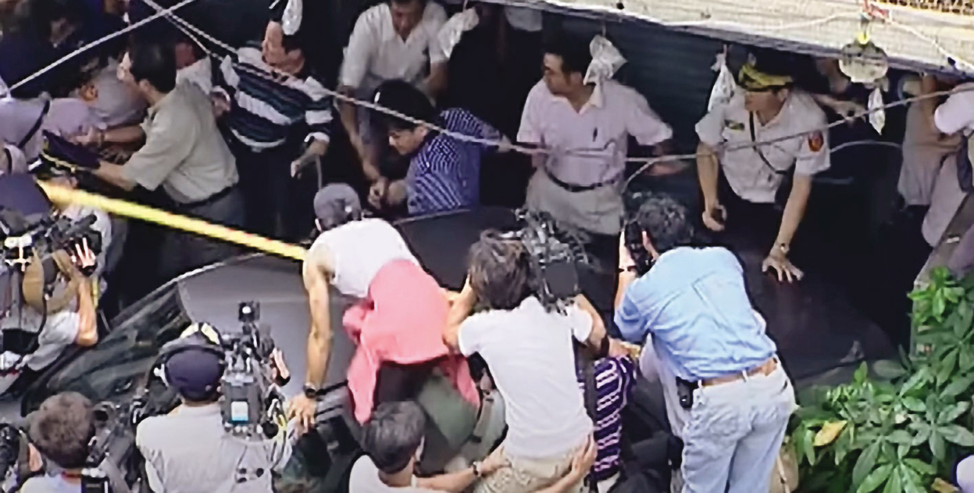 警方將凶手帶往現場模擬，氣憤的民眾上前追打，場面混亂。（翻攝東森新聞）