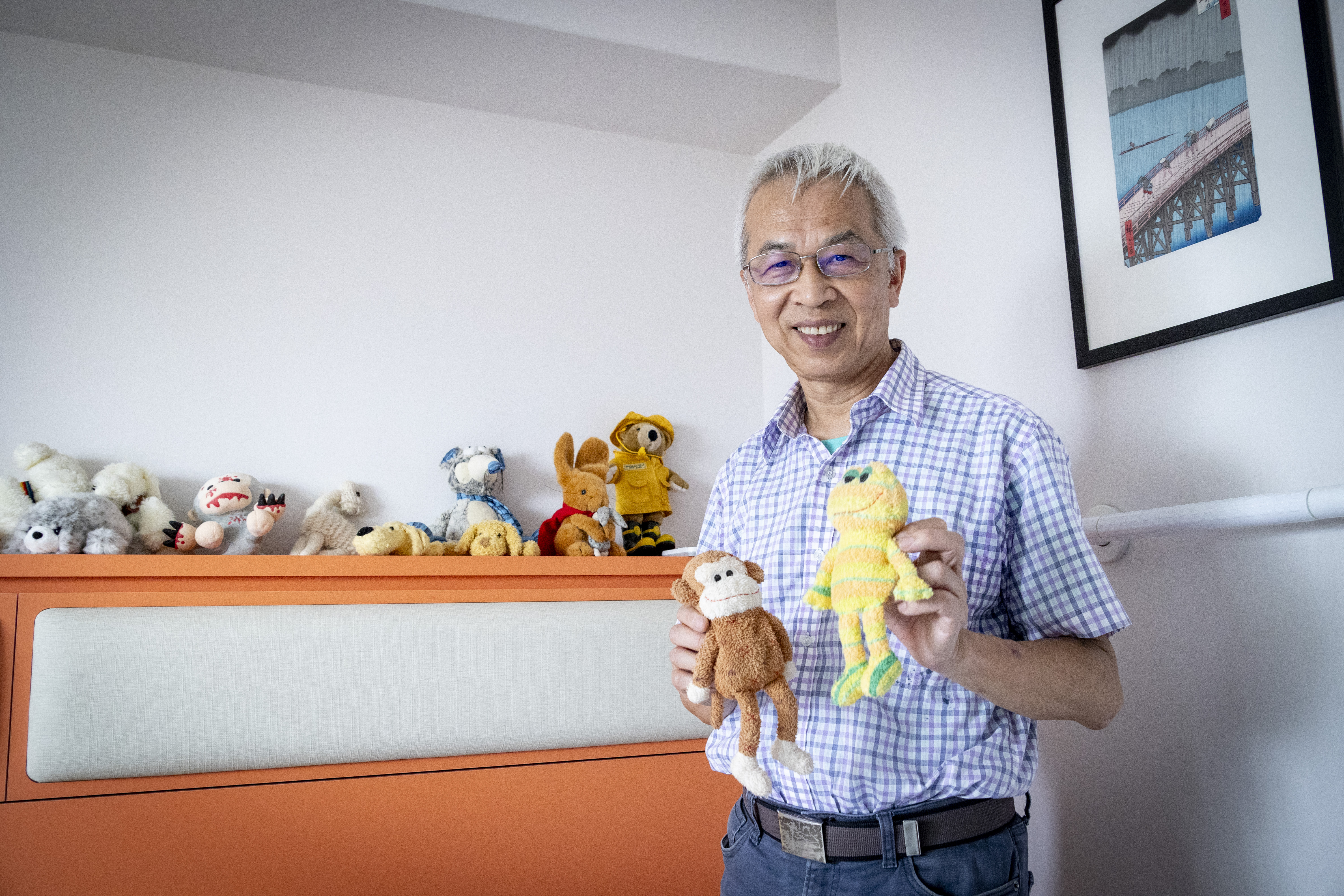 畢恆達舉起臥室的猴子和青蛙布偶，它們正是全台研究生寫論文必讀的《教授為什麼沒告訴我》封面本尊。