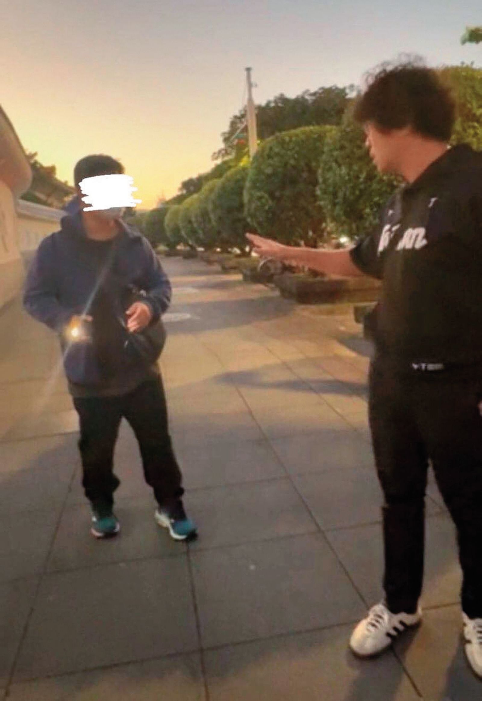 沈伯洋（右）去年底帶女兒在國家音樂廳旁散步，一名男子（左）突用手機強光照他，並錄影質問：「你在台灣也很危險嗎？」（翻攝沈伯洋臉書）