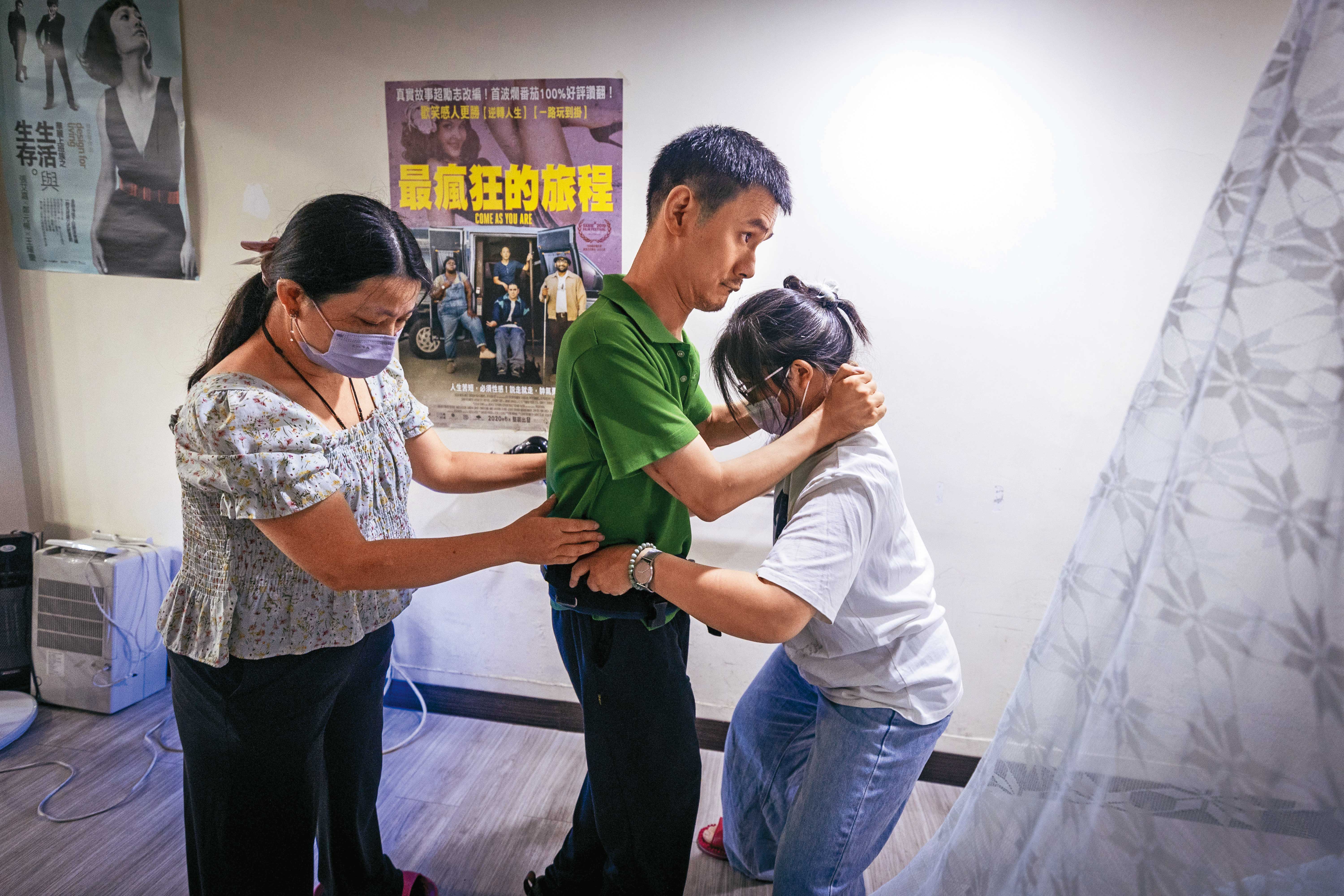 孫嘉梁（中）在物理治療師與個人助理的協助下練習行走。