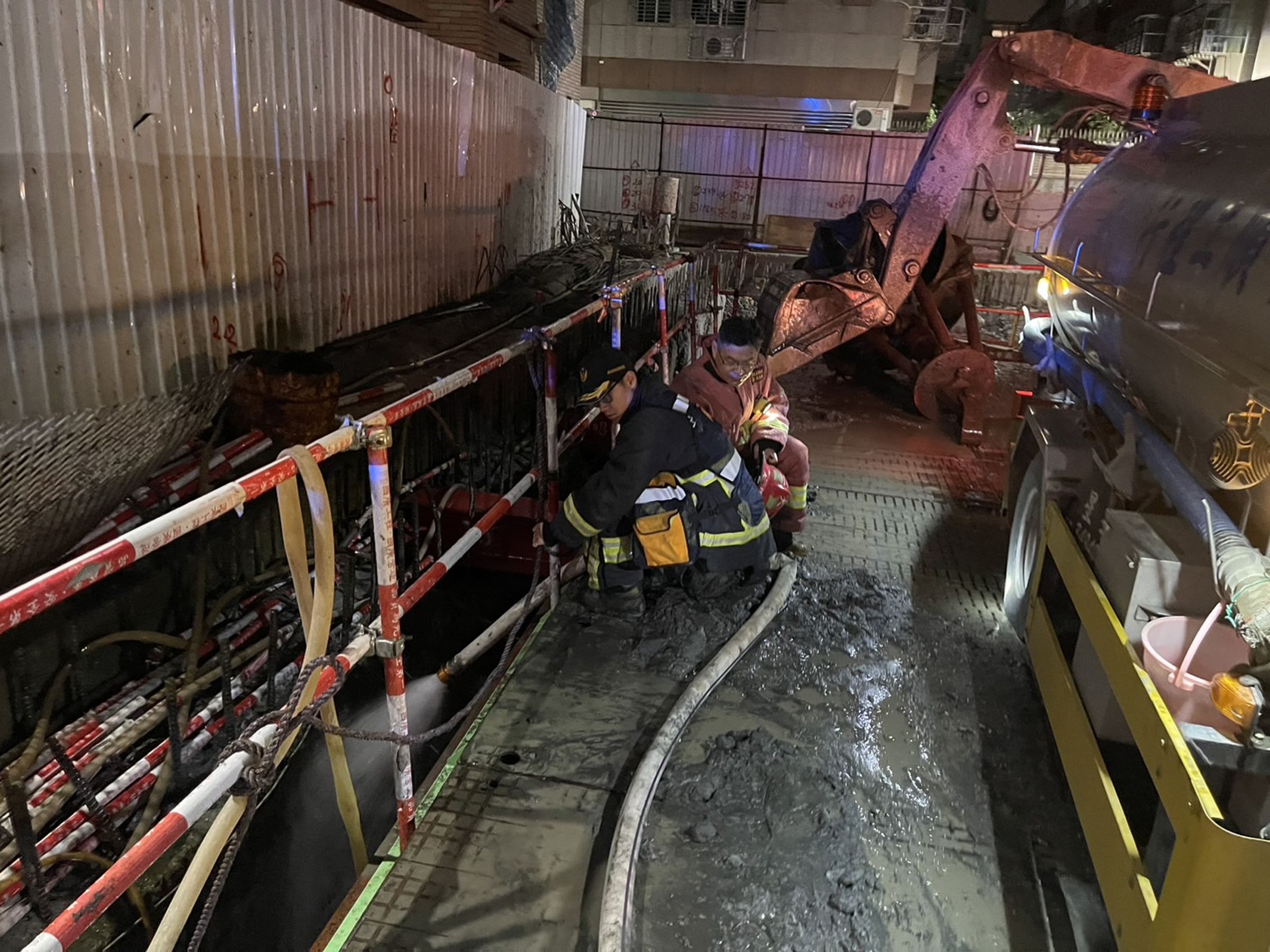 新北市三重區福隆路一處新建大樓工地,下午因地下室連續壁破洞,導致地下水往工地流,造成一旁大樓傾斜。(翻攝畫面)