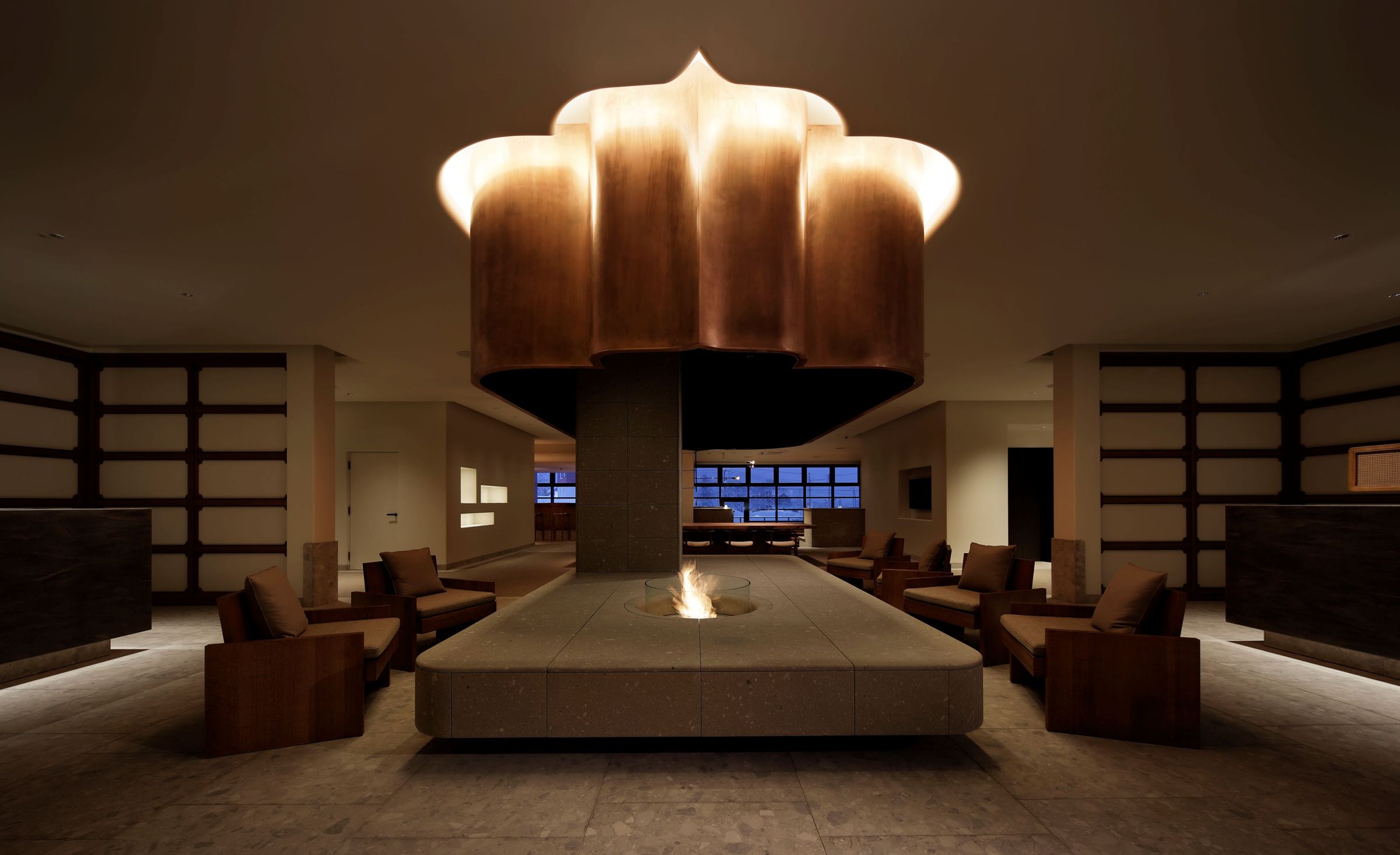 「Chatrium Niseko Japan」的大廳中央設有暖心爐台,搭配造型獨特的藝術吊燈與舒適沙發區,為賓客提供一處沉靜而溫暖的迎賓之所。(Chatrium Niseko Japan)