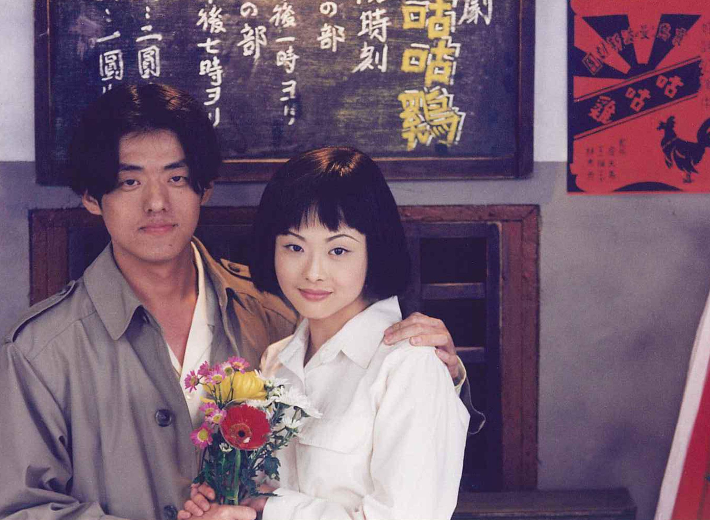 林強手捧鮮花輕摟蕭淑慎，兩人在劇團黑板前，詮釋《天馬茶房》中知識青年與演員在動盪時代下的苦戀。（青睞提供）
