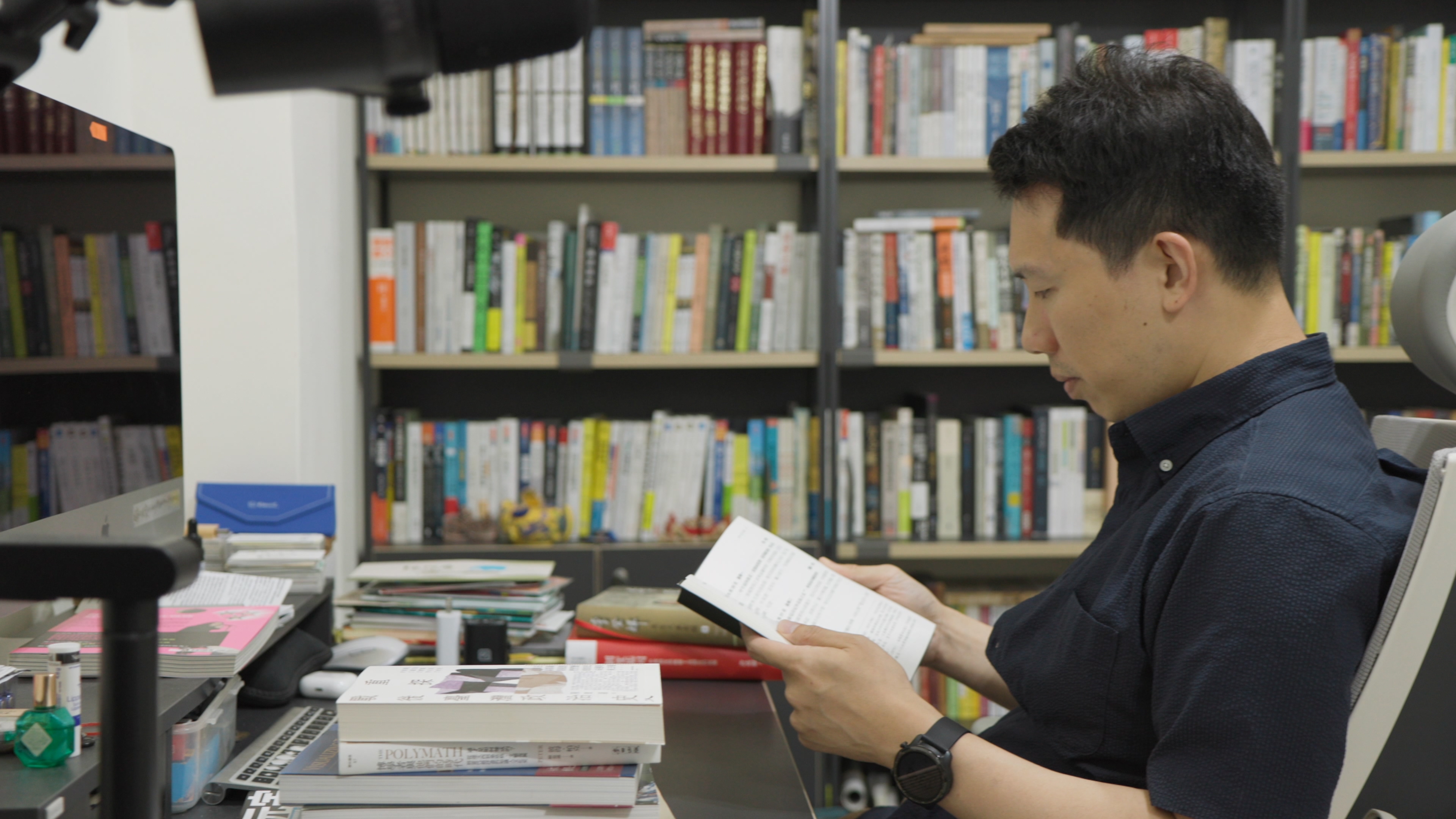 涂豐恩閱讀時不需要特別的空間或儀式，桌上常常堆著一落「待命」的書籍，隨時翻讀。（公視提供）