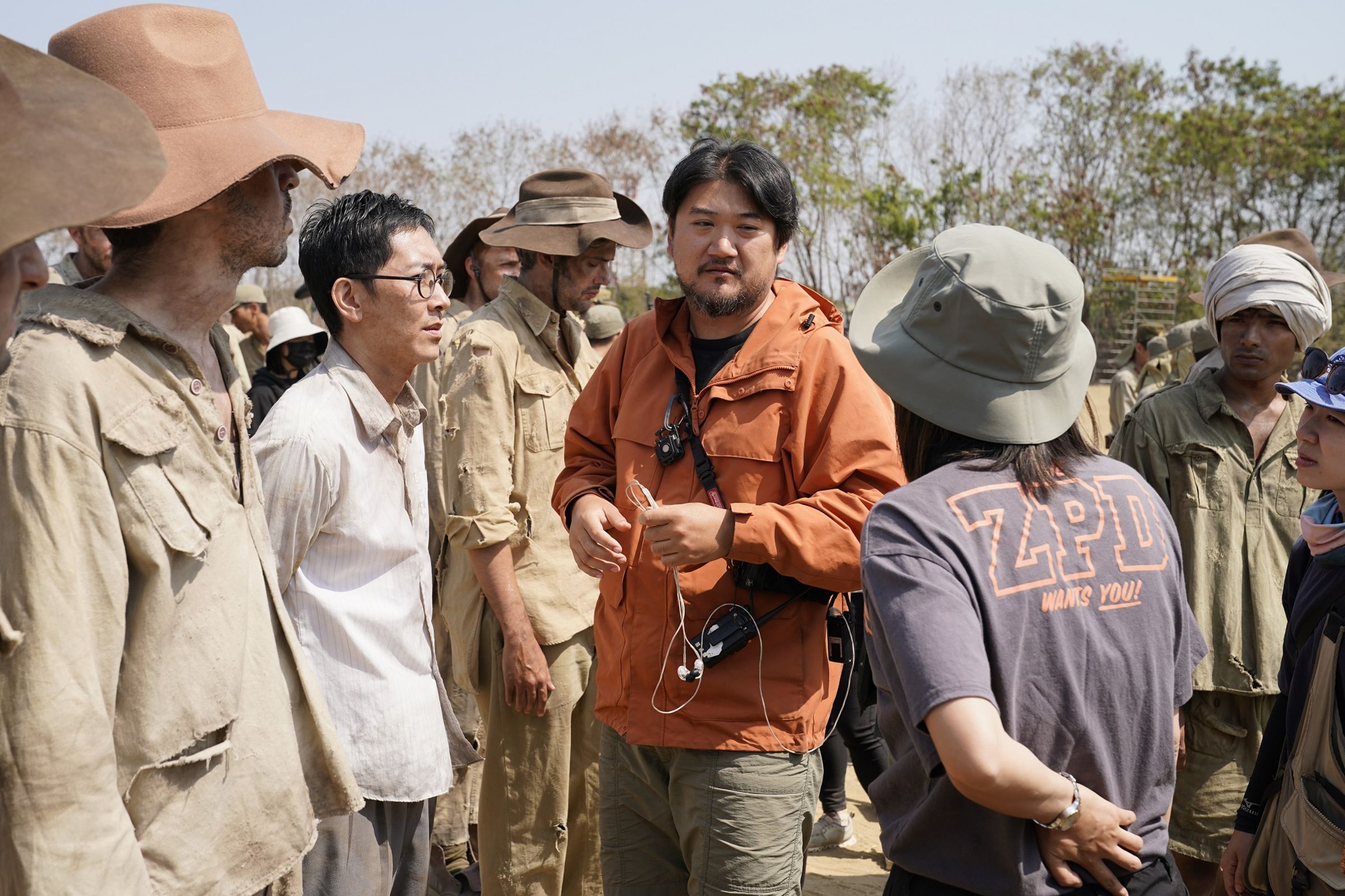 導演孫介珩(中)在高雄南星計畫區整地填土搭建《聽海湧》戰俘營主景,並於當地徵求外籍臨演飾演俘虜。左二為施名帥。(公視提供)