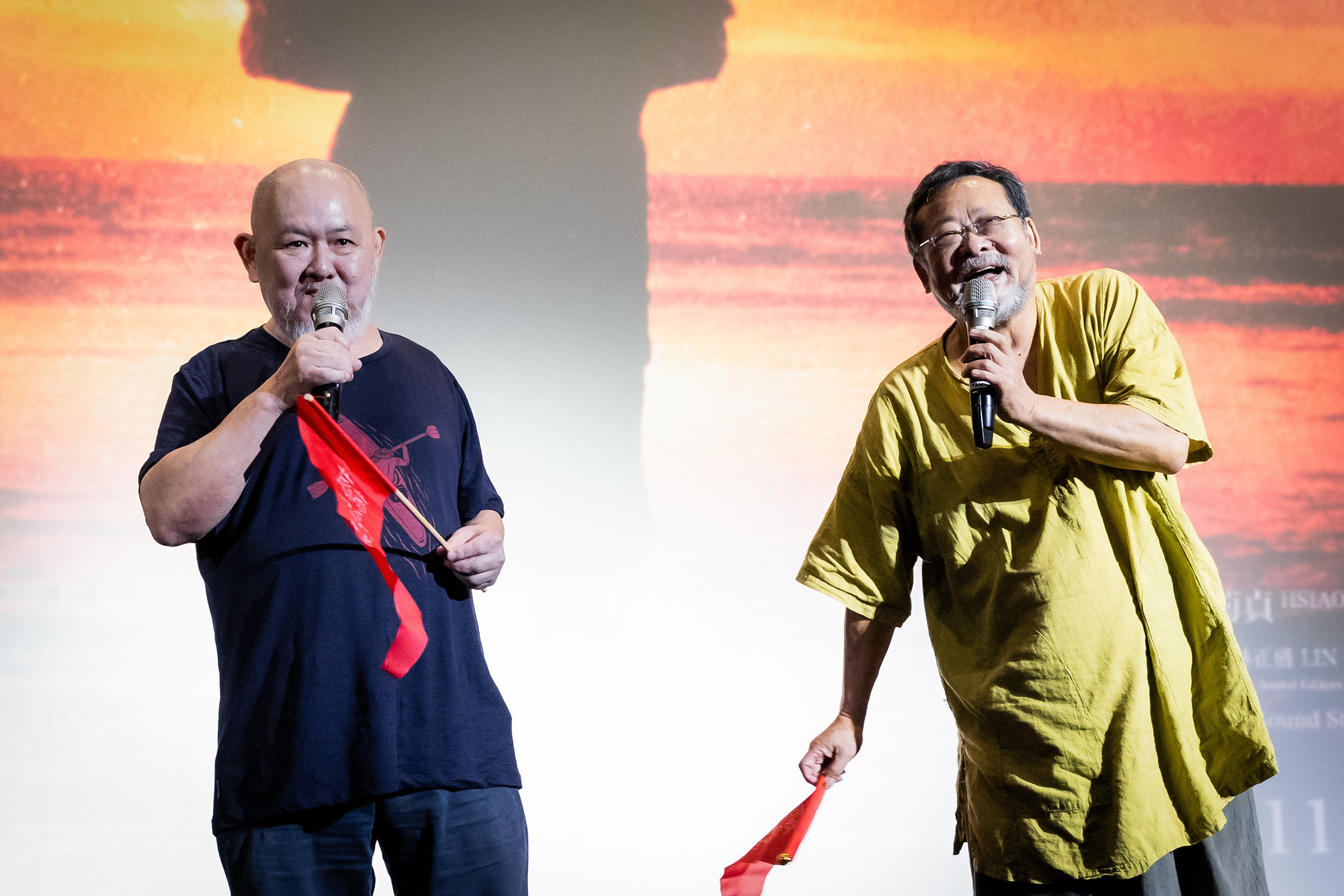 《撼山河 撼向世界》陳明章（右）與導演林正盛（左）在映後帶領觀眾一齊揮舞手中的紅旗。（我們之間影像製作有限公司提供）
