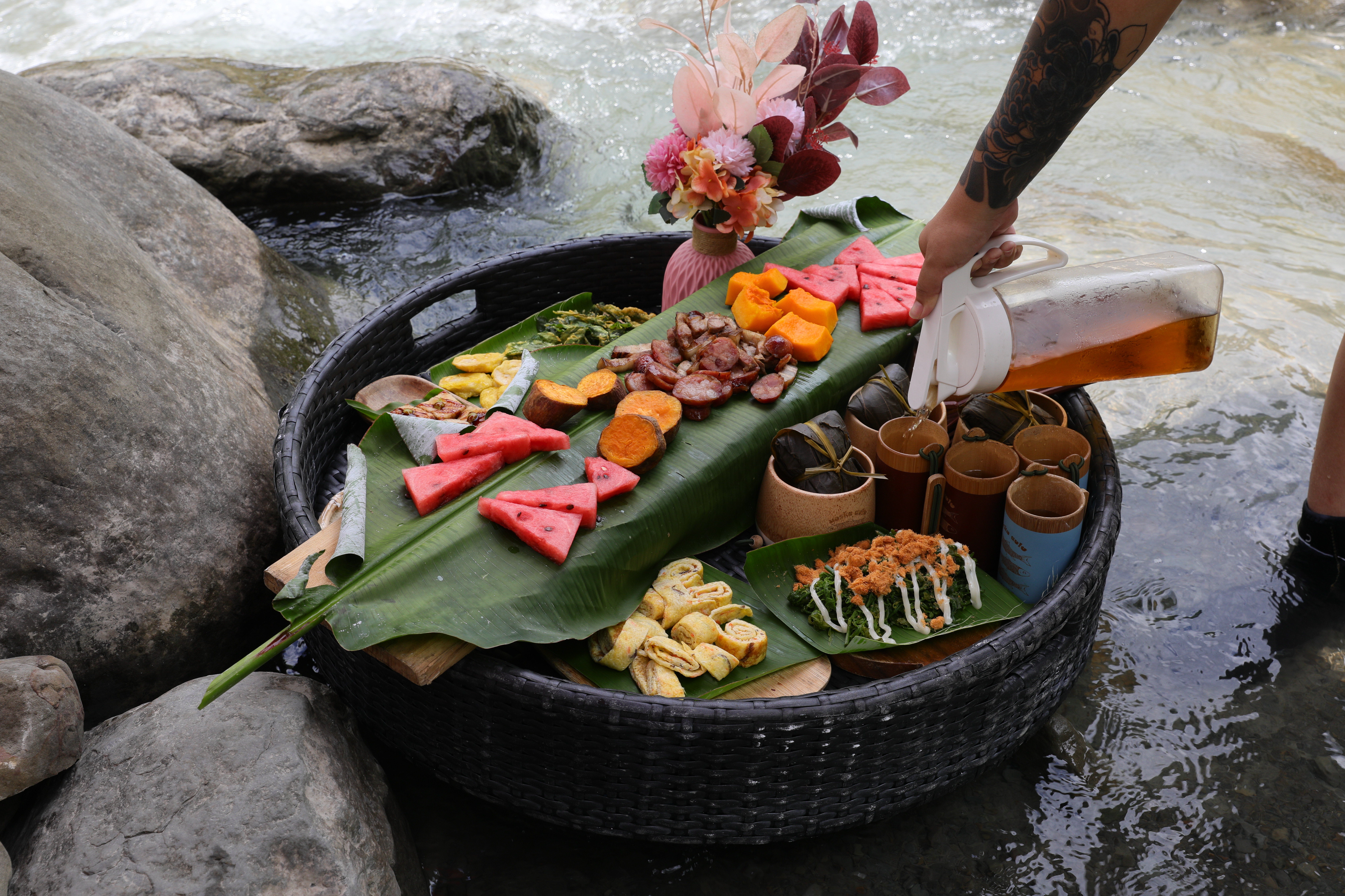 「水上餐」將菜式裝進竹籃內，漂浮於溪水之上，讓佳餚不僅能在餐桌上享用，也能在自然溪流中品味。
