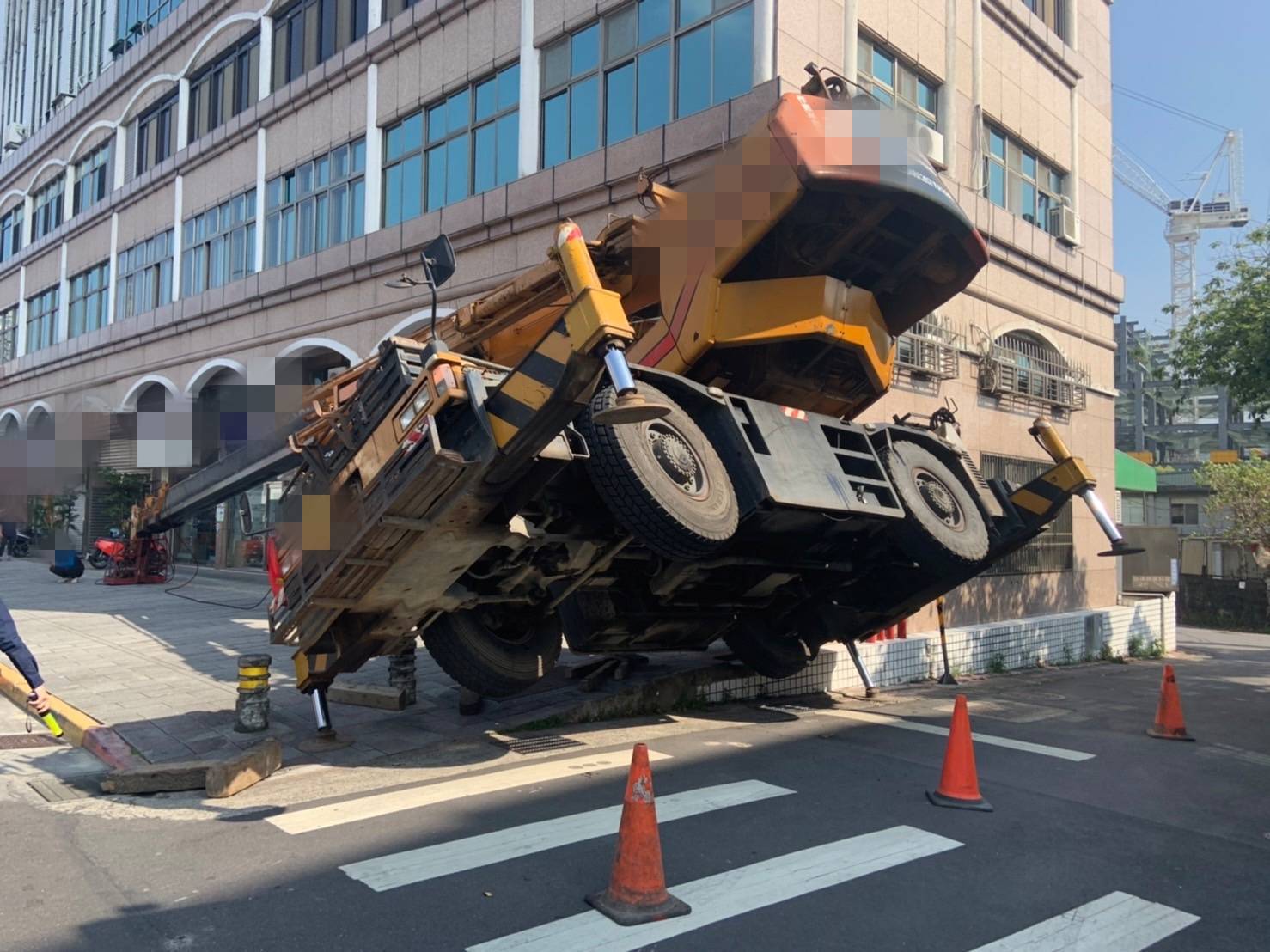 北市南港路三段一處大樓旁有吊車傾斜四輪懸空，場面嚇人。（翻攝畫面）