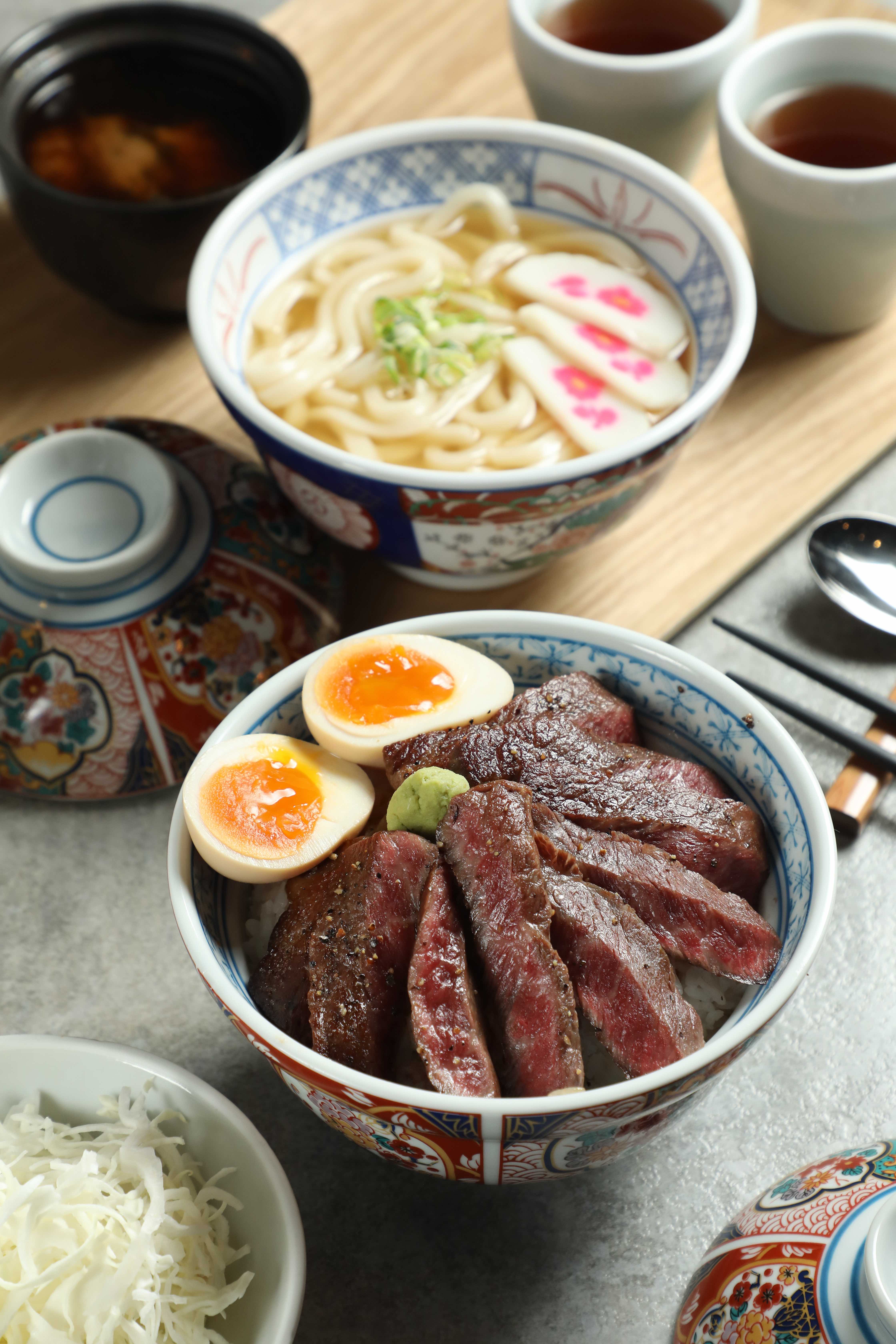「和牛牛排丼」（前，600元／份）厚切和牛經炙烤後香氣四溢，呈現和牛的油脂風味；「出汁烏冬」（後，130元／份）以日式高湯襯托和牛鮮甜，Q彈烏龍麵吸附滿滿湯汁精華。