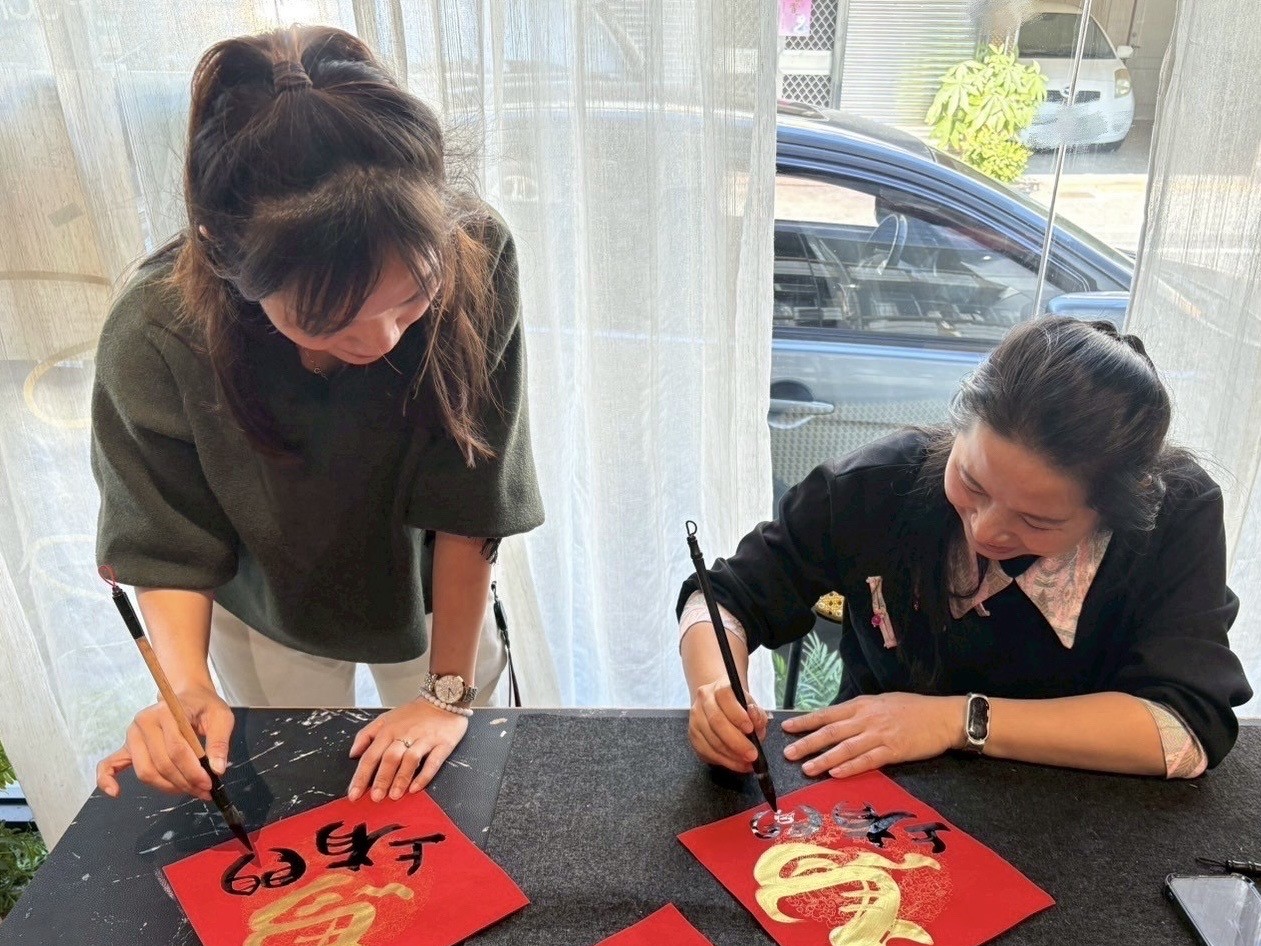 藝術家申婷頡(右)和新住民一起揮毫創意春聯。（移民署提供）
