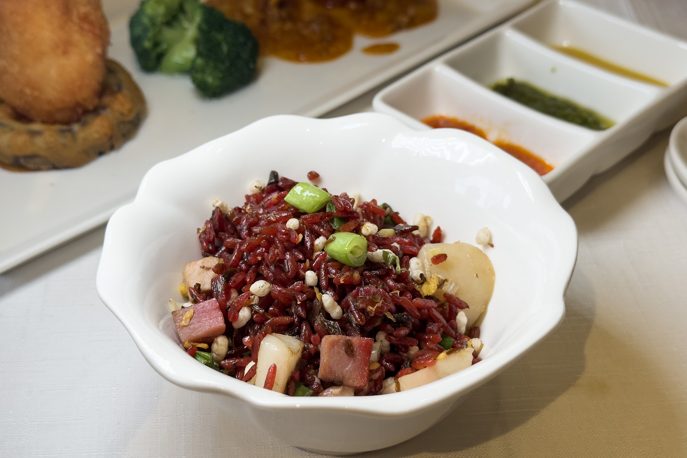 為了吸引挑食的兒子吃飯，章師傅以紅菜頭汁蒸煮米飯，拌入鮮干貝丁、梅乾菜、叉燒等配料，讓「梅菜叉燒帶子粒炒脆紅米飯」色香味俱全。