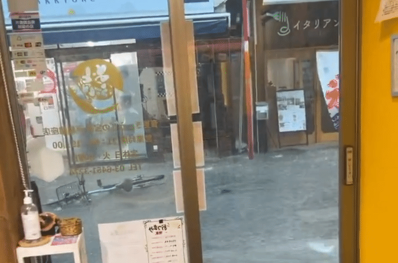 東京品川的戶越銀座商店街今下午因暴雨被淹成了一條小河，自行車等物品從店家門口漂過。（翻攝自X @otofuke_gyoza）