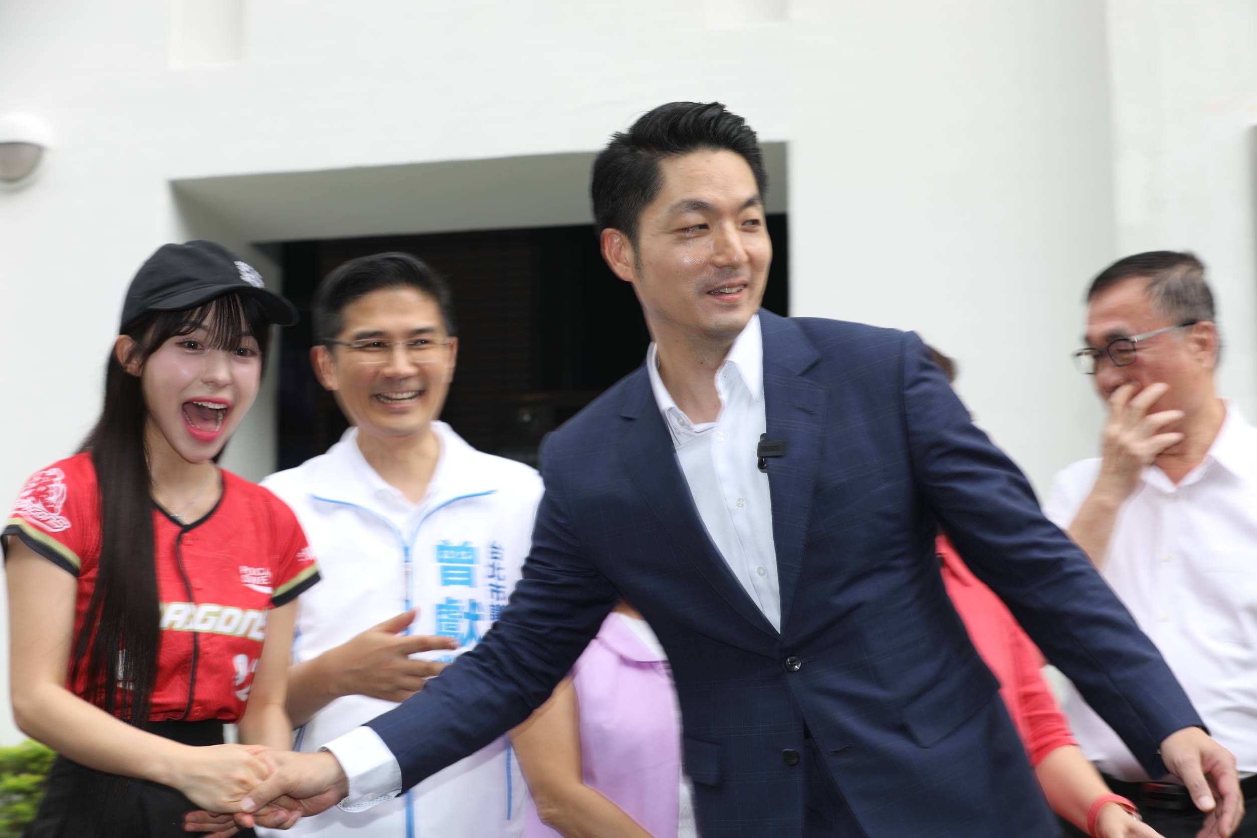 蔣萬安在青年局外揭牌合影時，主動牽著李多慧的手把他帶到C位同框。