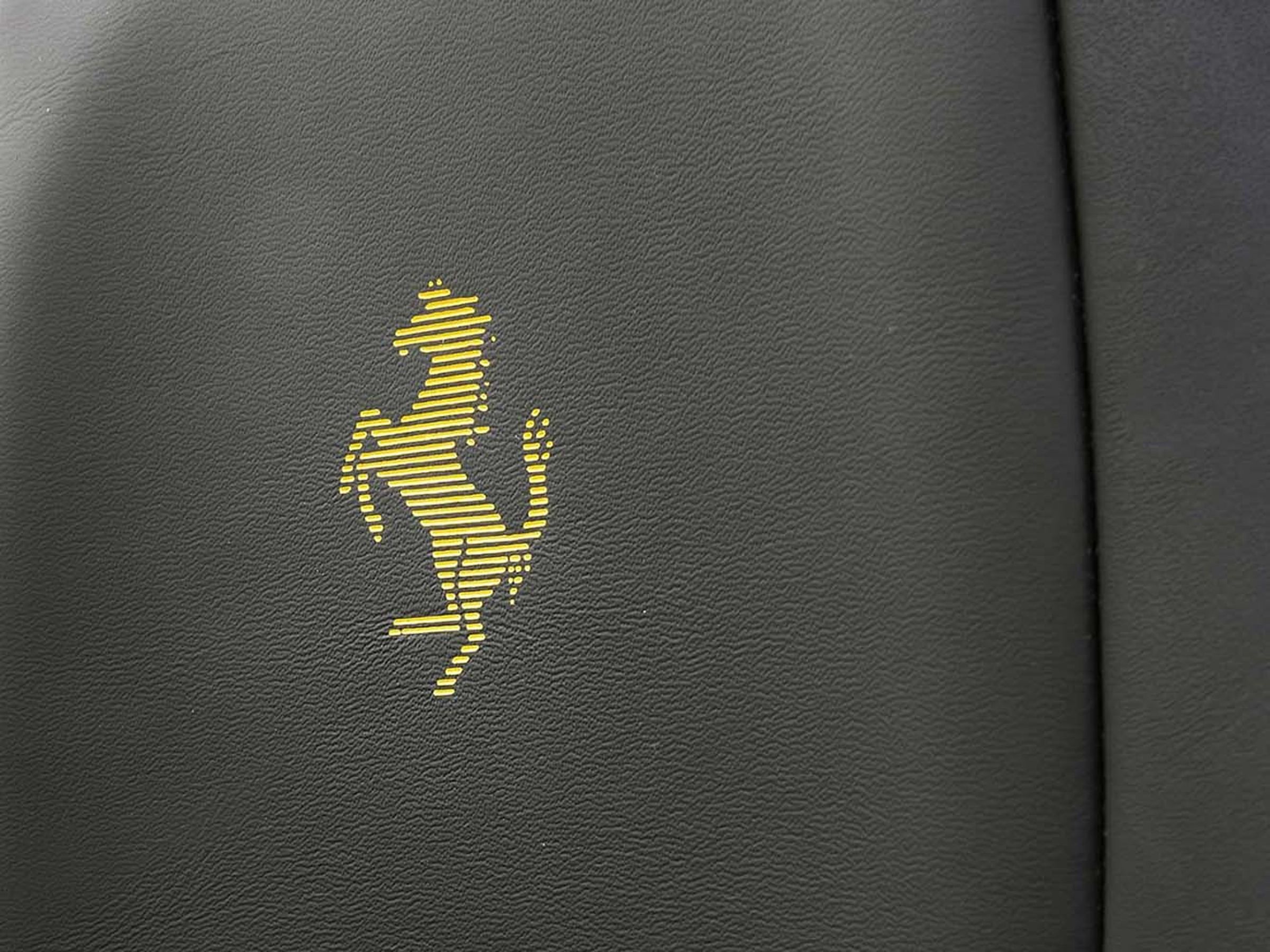 來自 Ferrari 廠徽與煞車卡鉗的黃色元素,則點綴於縫線與飾板細節,營造鮮明對比。