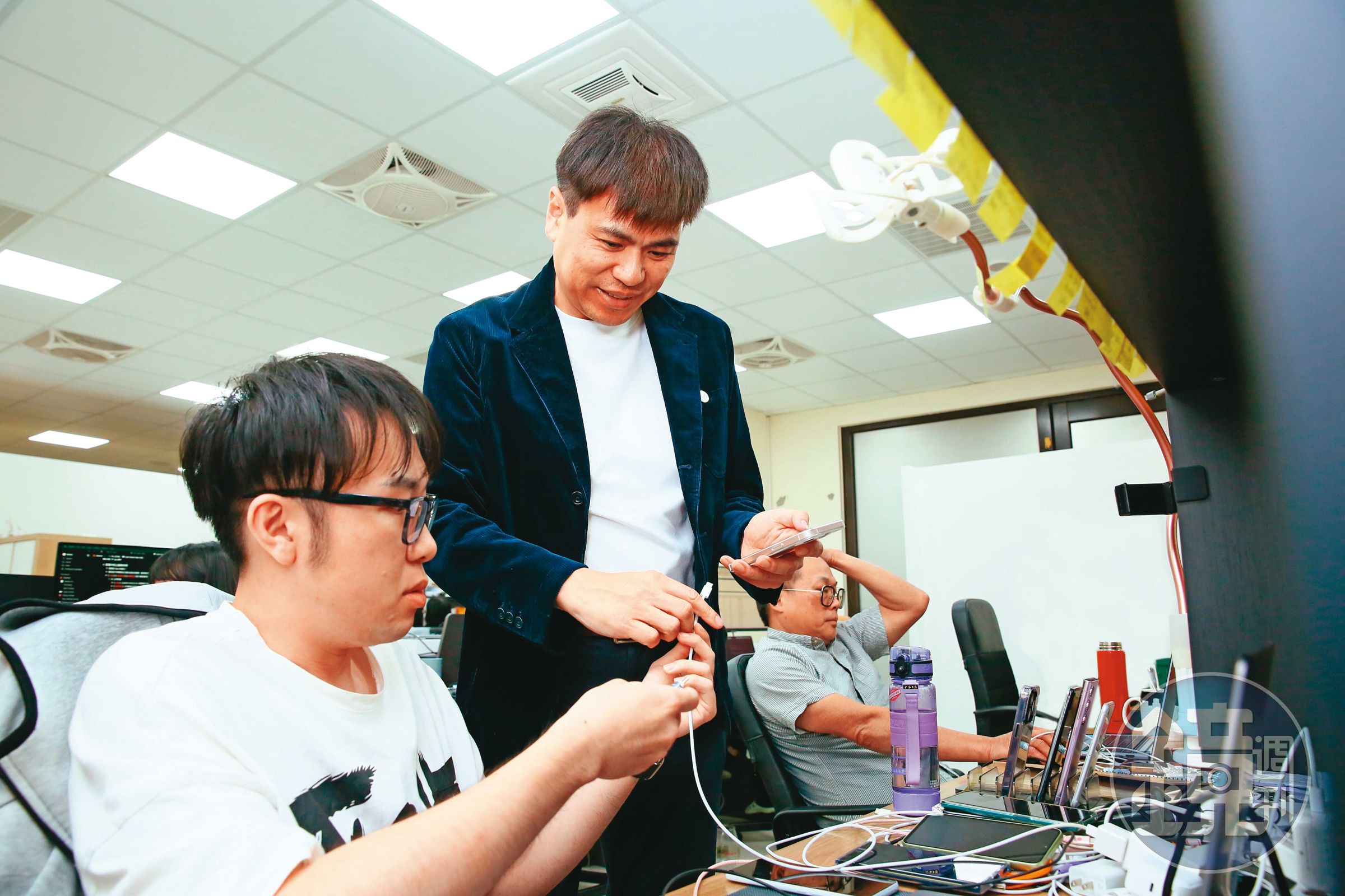 圖中站立者為陳良信，為了讓自家產品在Android系統上也能使用，他測試遍了市面上所有大品牌手機。