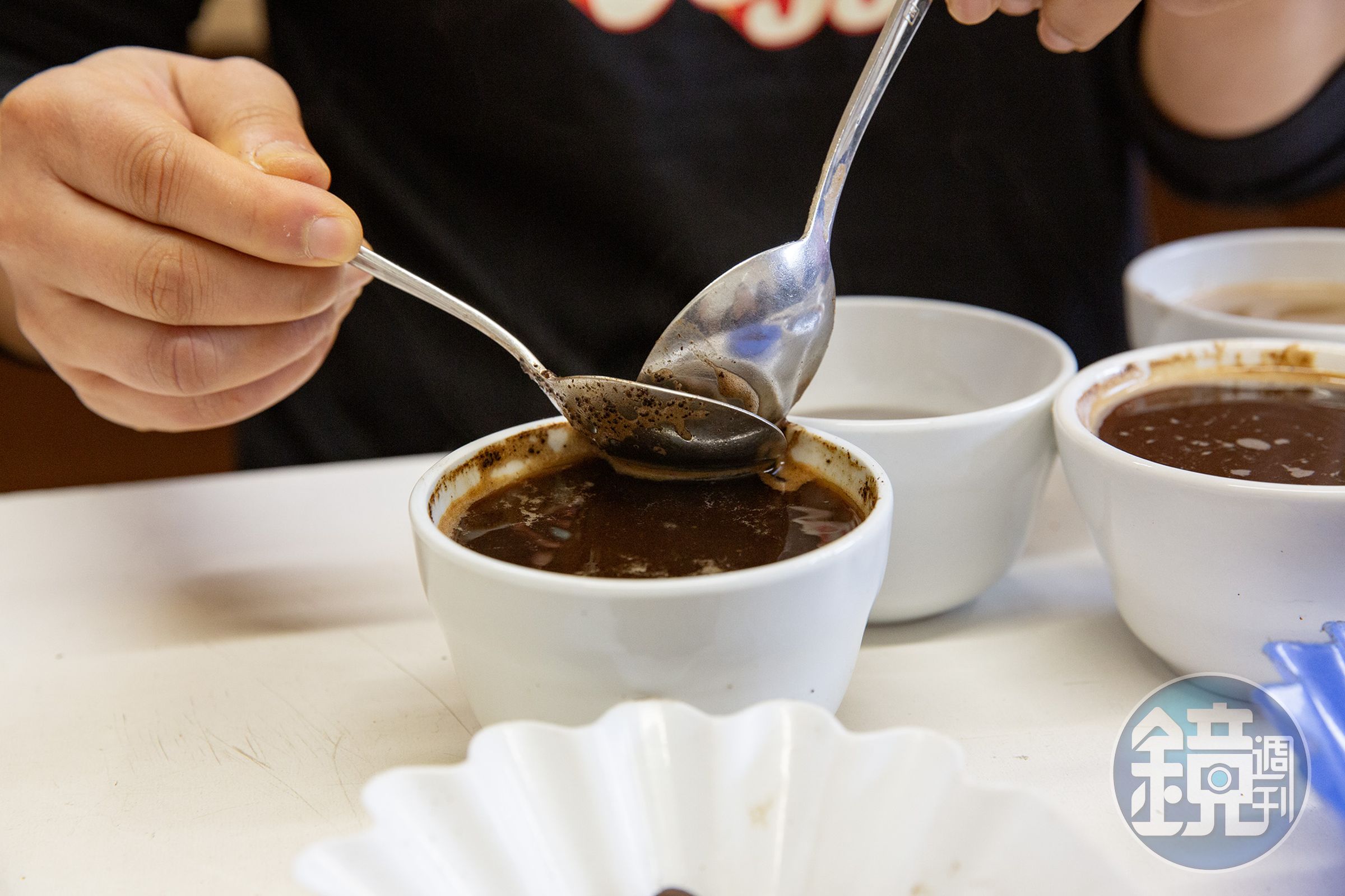 Faye為我們示範烘豆師日常的杯測流程,她將研磨咖啡粉以熱水浸泡,再逐杯啜飲比較香氣、酸度與口感。
