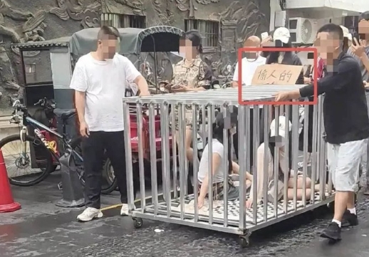 湖南汨羅市街頭昨日驚見清涼口罩女與小黑狗遭關進鋼籠遊街。（翻攝自微博）