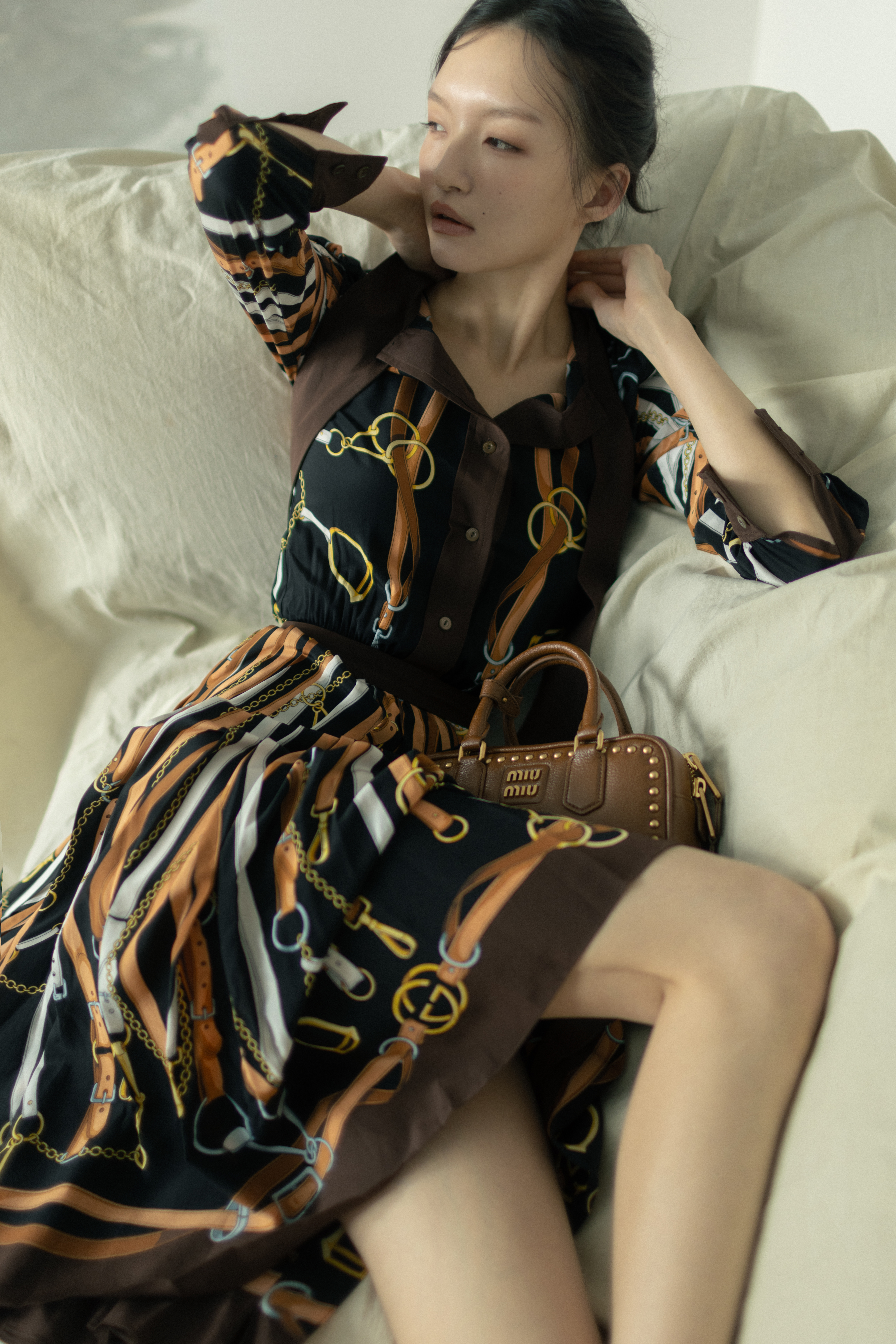 絲質印花洋裝 NT$153,500 by GUCCI;鉚釘裝飾Arcadie皮革手提包 NT$135,000 by MIU MIU。
