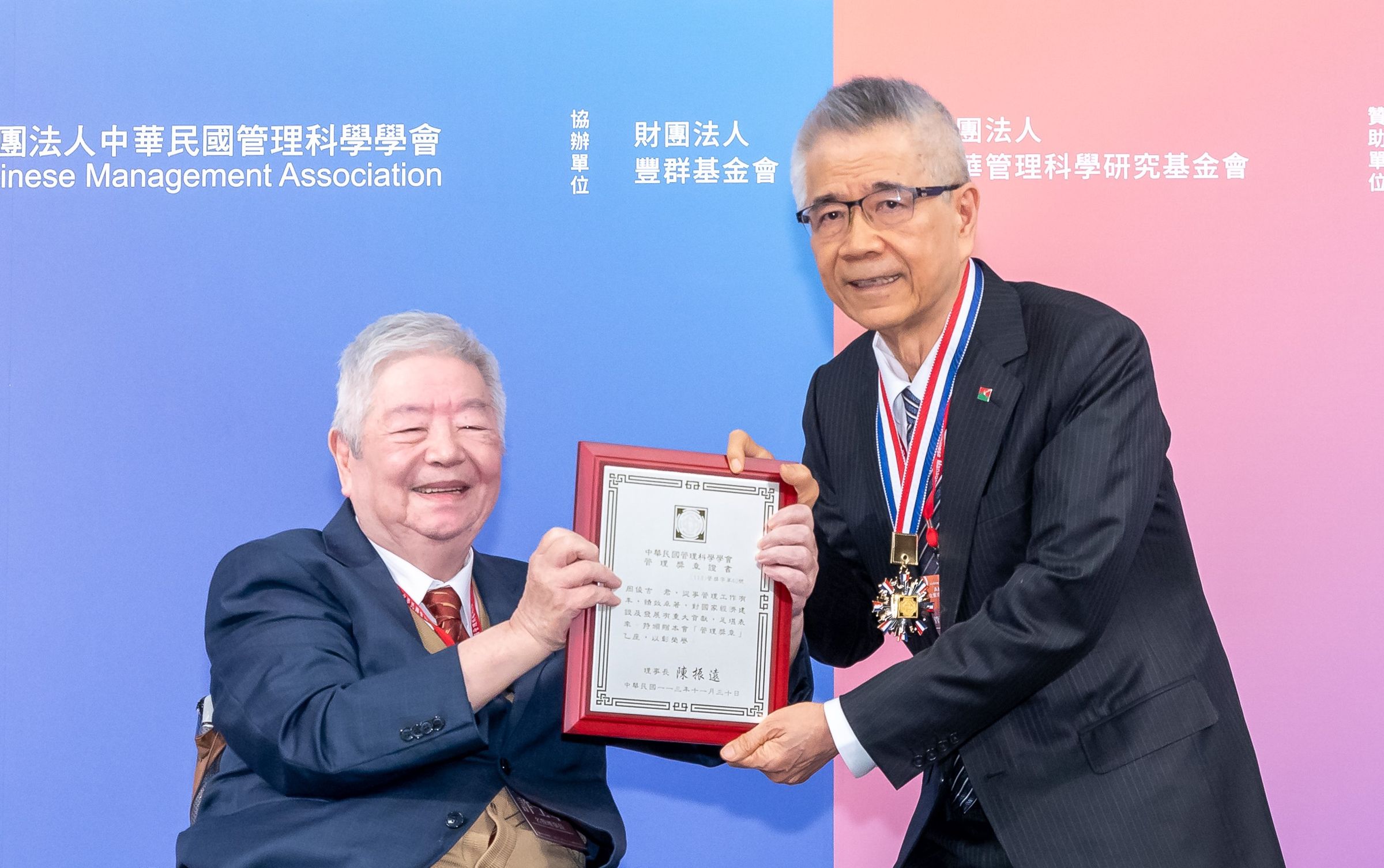 中華民國管理科學學會名譽理事長許士軍(左)頒發管理獎章榮譽給信義企業集團創辦人周俊吉。(信義房屋提供)