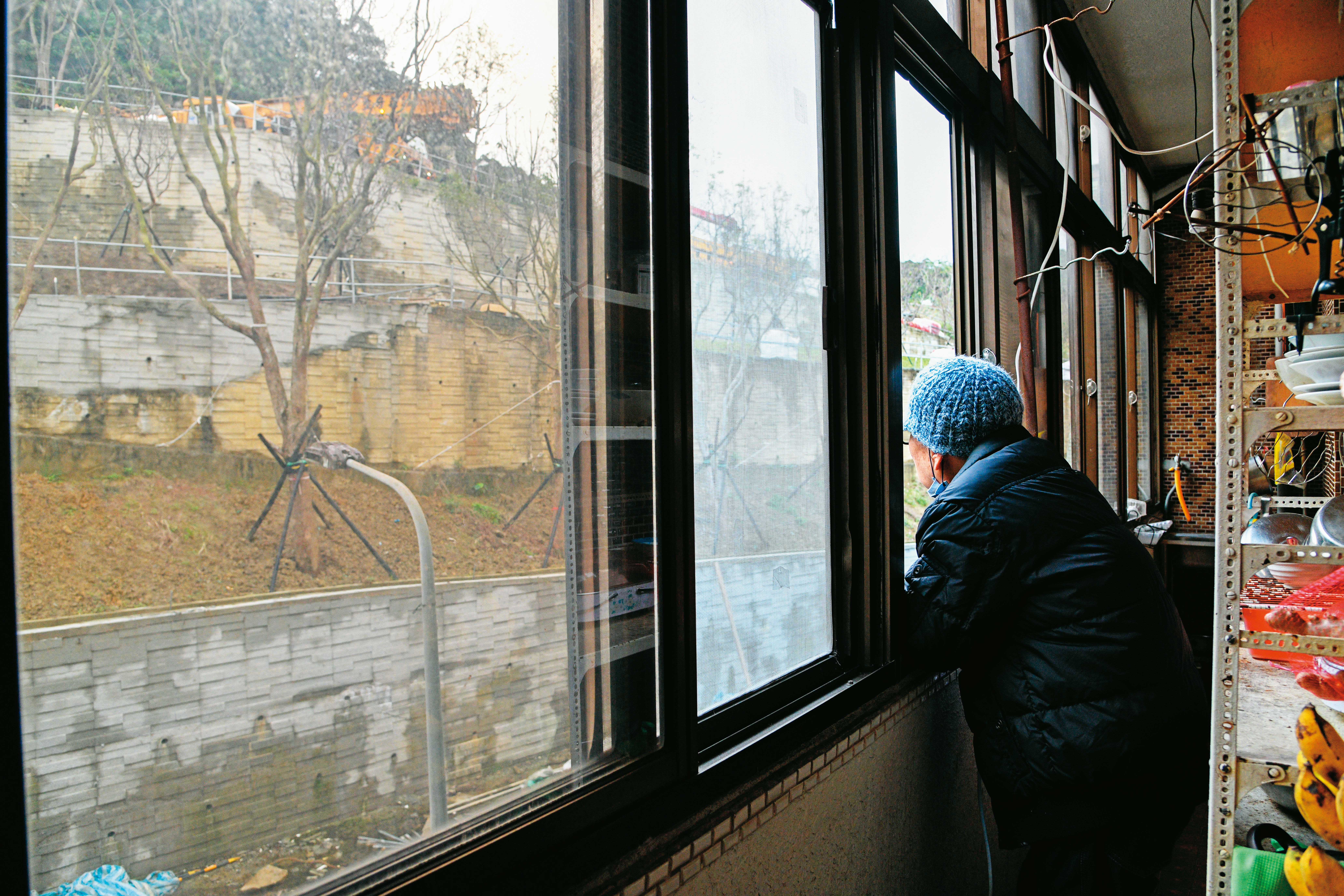 居民A先生無奈地看著自家對面高聳的擋土牆，希望蔣市府主持公道。