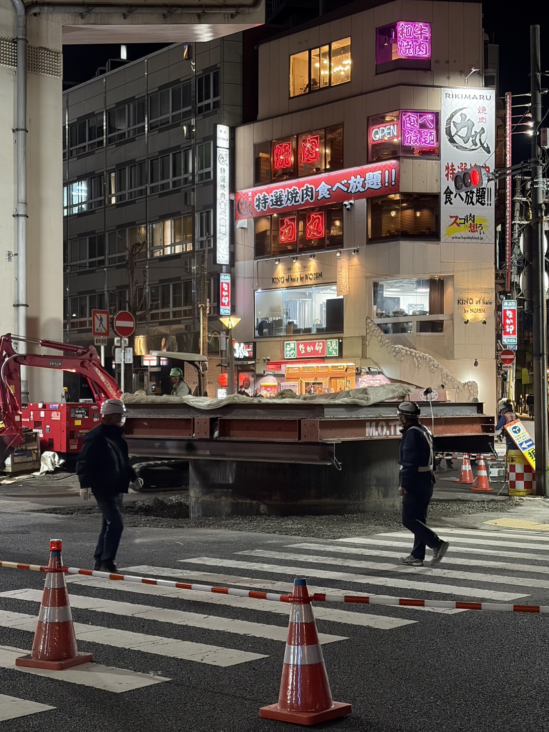 日本大阪梅田路面突然冒出13公尺高巨管，在相關工作人員緊急搶修下，巨管已漸漸下沉。（讀者提供）