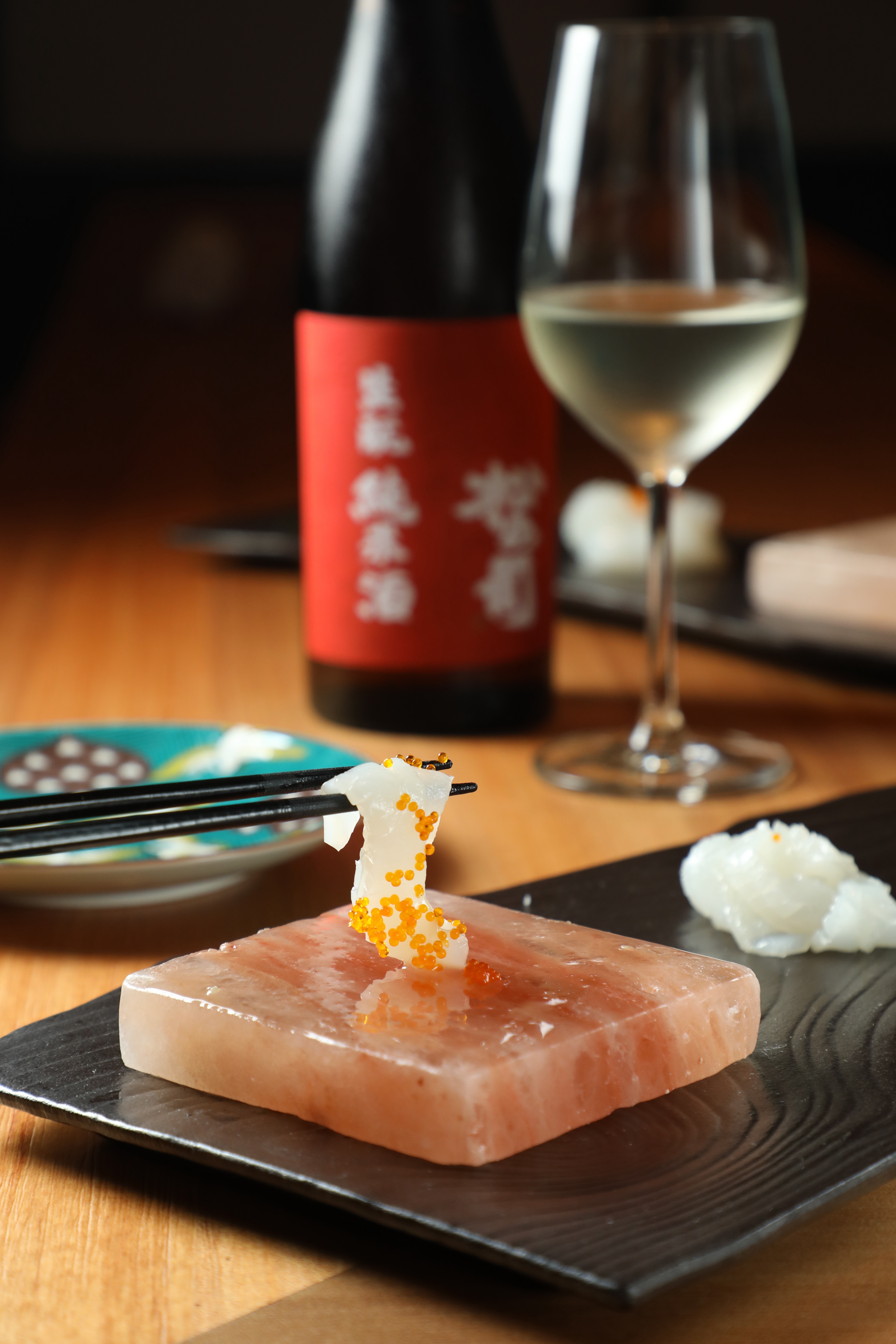 選用東港當季花枝的「花枝與飛魚卵刺身」（前），搭配來自日本滋賀縣龍王町松瀨酒造的「松之司 純米酒 生酛」（後），以古老的生酛自然發酵法釀製而成。（酒款為晚間套餐限定）