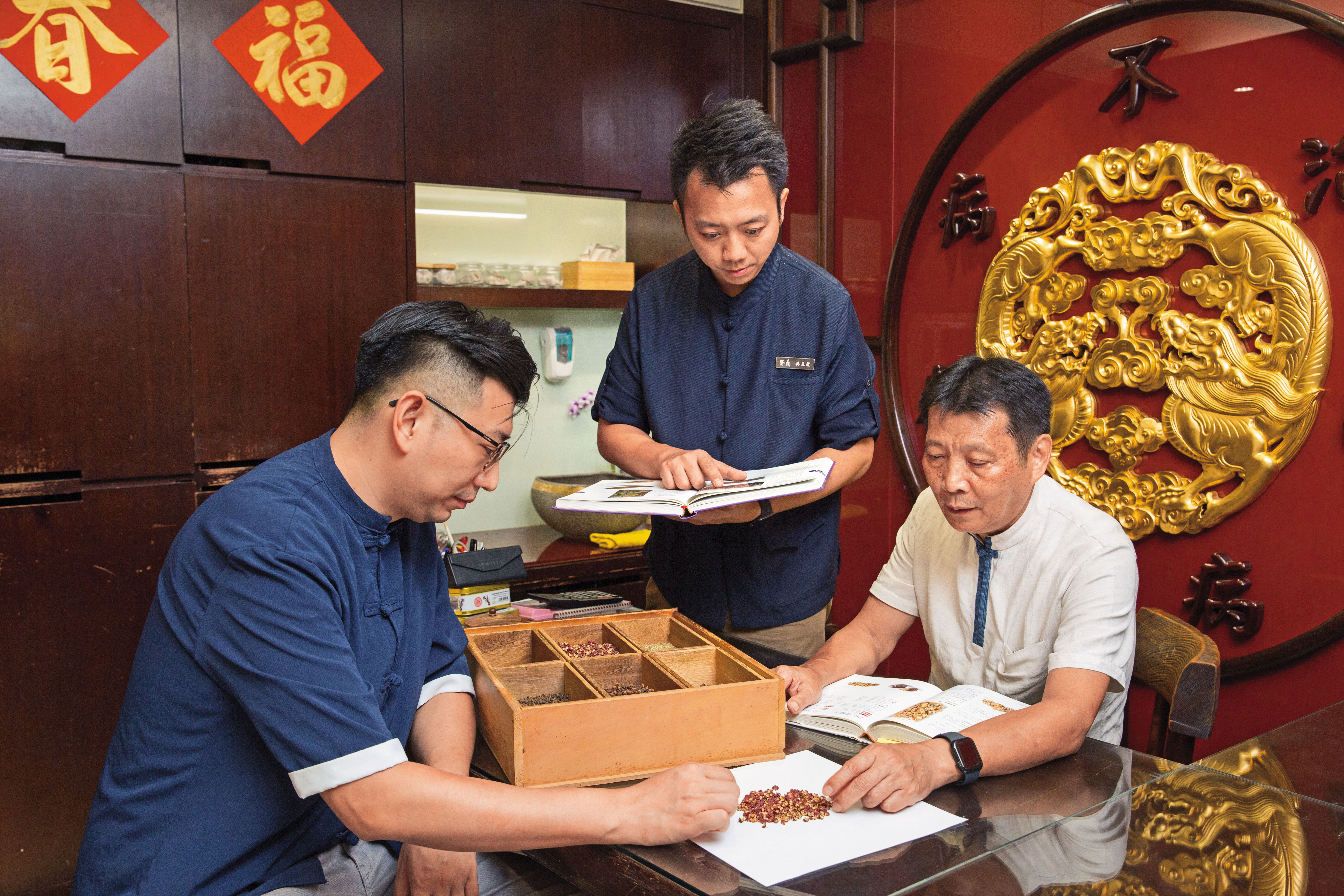 吳瀛洲（右）是店內的中藥活字典，兒子吳孟龍（中）與吳孟宸（左）常與他討論藥材應用。