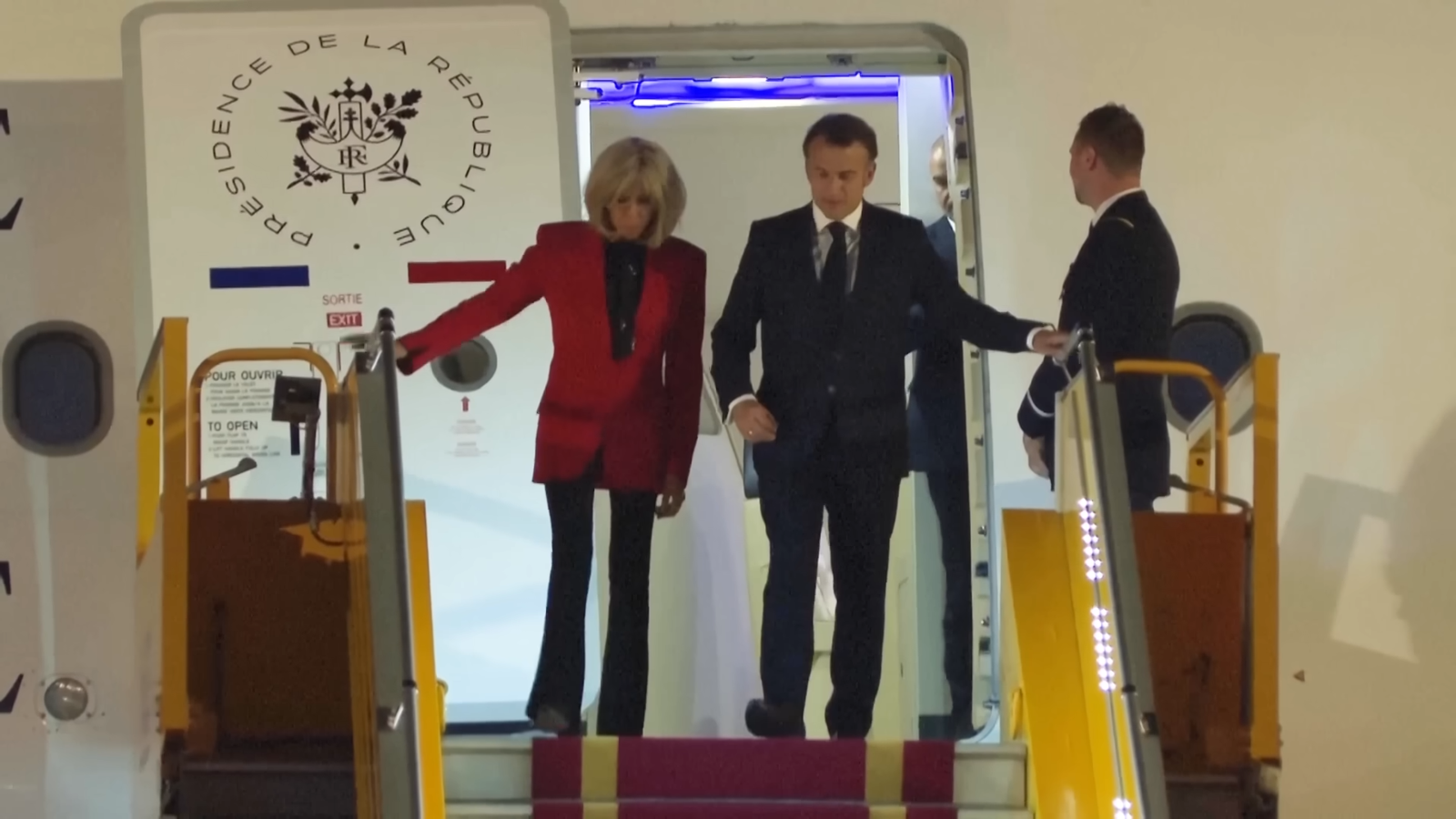 馬克宏似乎空出右手要讓夫人攙扶，但夫人卻逕自抓著登機梯的欄杆往下走。（翻攝自YouTube）