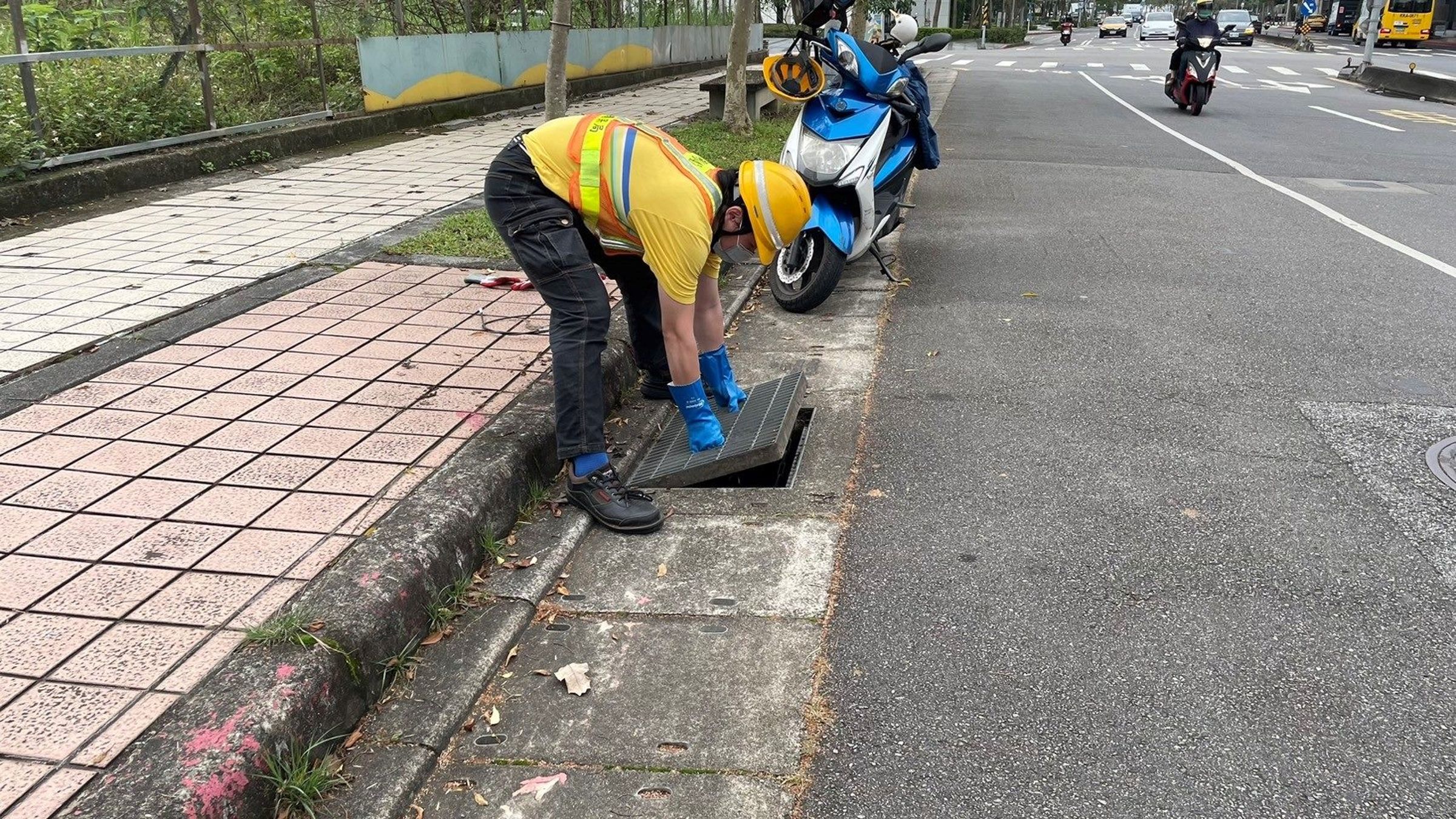 清潔隊員戴上橡膠手套,打開水溝井蓋尋找民眾掉落的失物。(北市環保局提供)