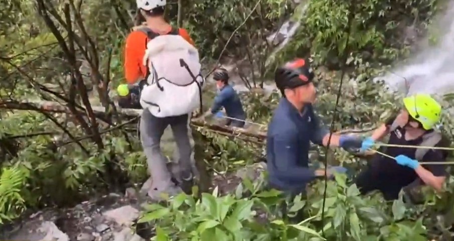 台中蝴蝶谷步道發生落石意外造成4人死亡，救難人員冒雨救援，直到晚間9點才將遺體運抵登山口。（翻攝畫面）