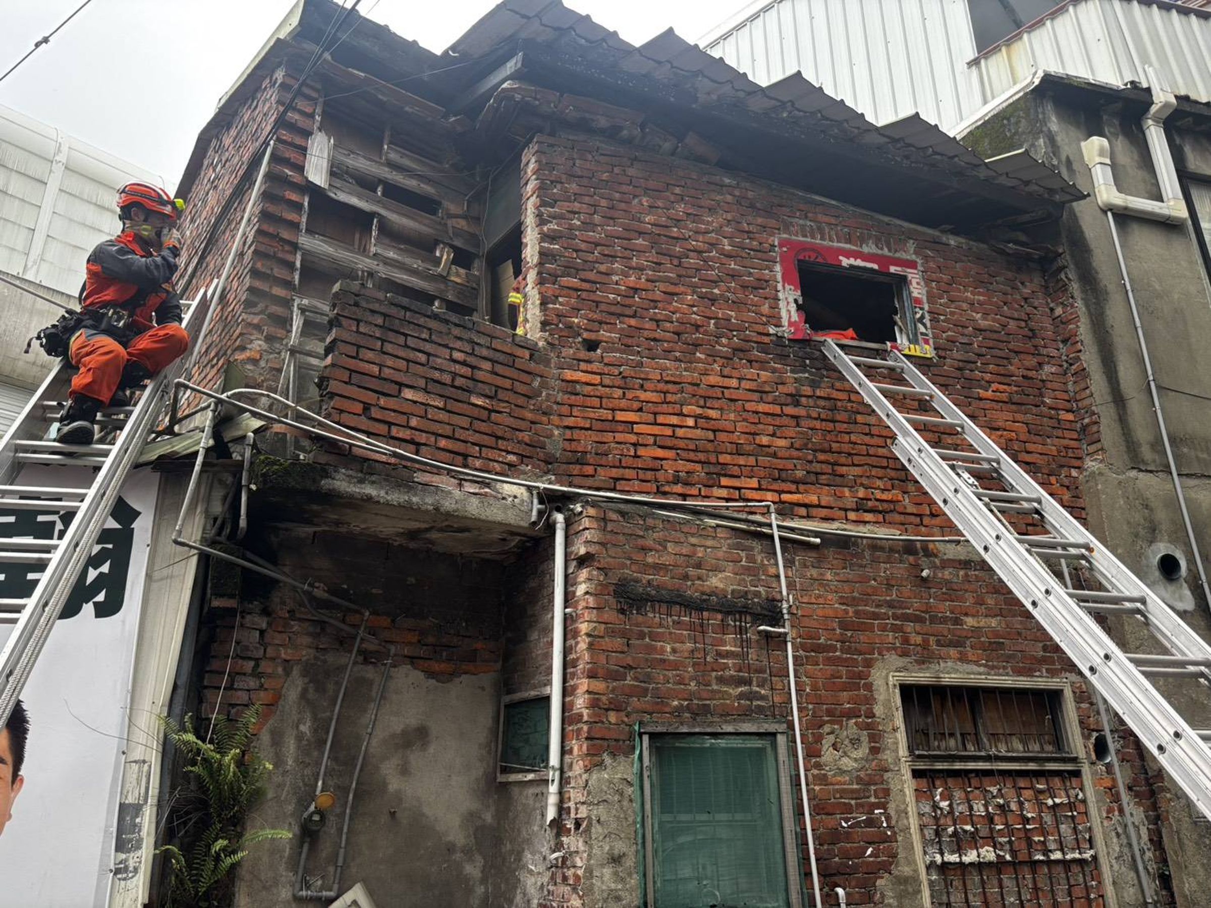土城二層樓磚造老宅，今日下午傳出屋頂瓦片坍塌，消防人員冒險上樓救出受困住戶。（翻攝畫面）