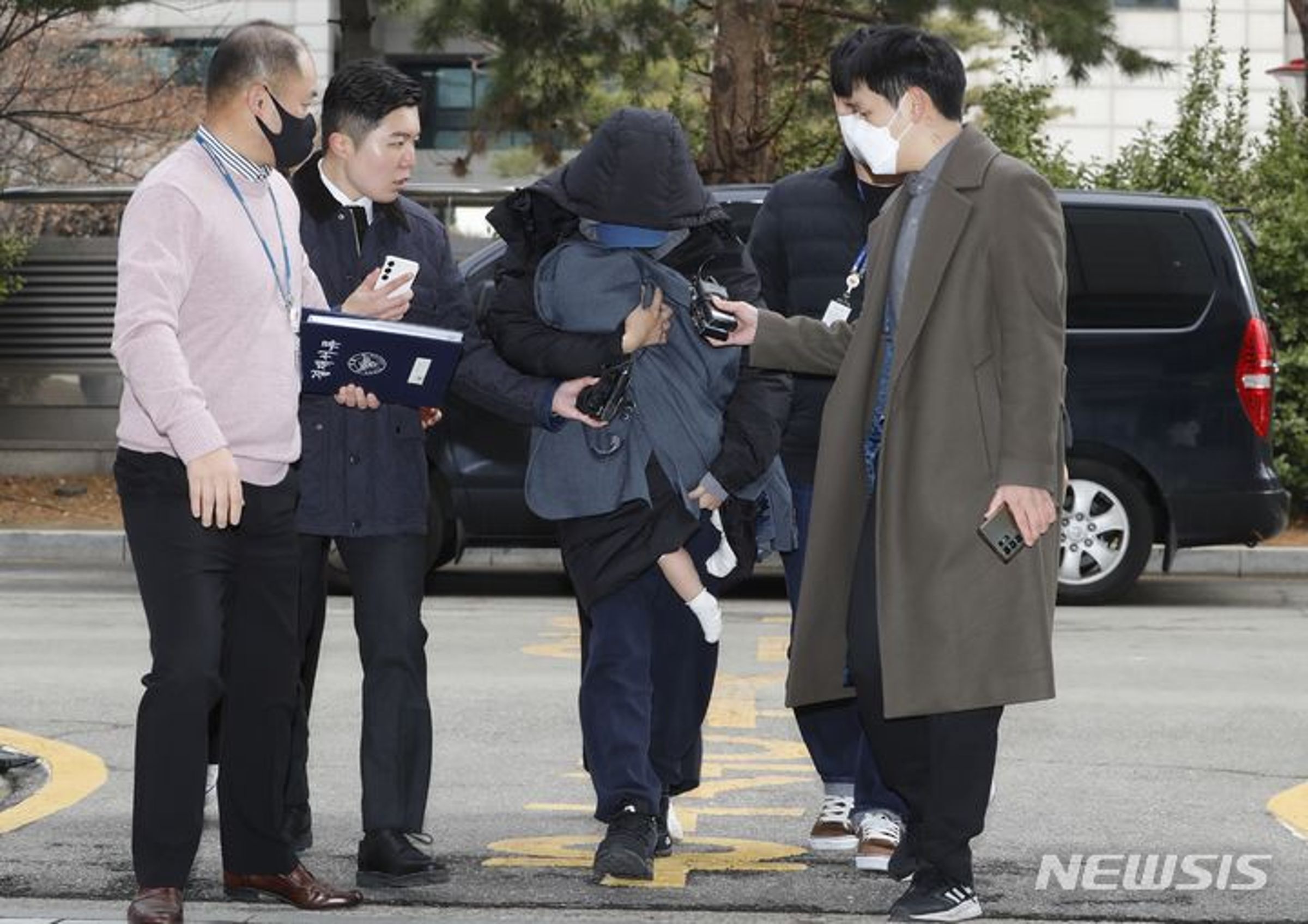 A女抱著小孩走向法院,面對記者詢問默默不語。(翻攝spotvnews網站)