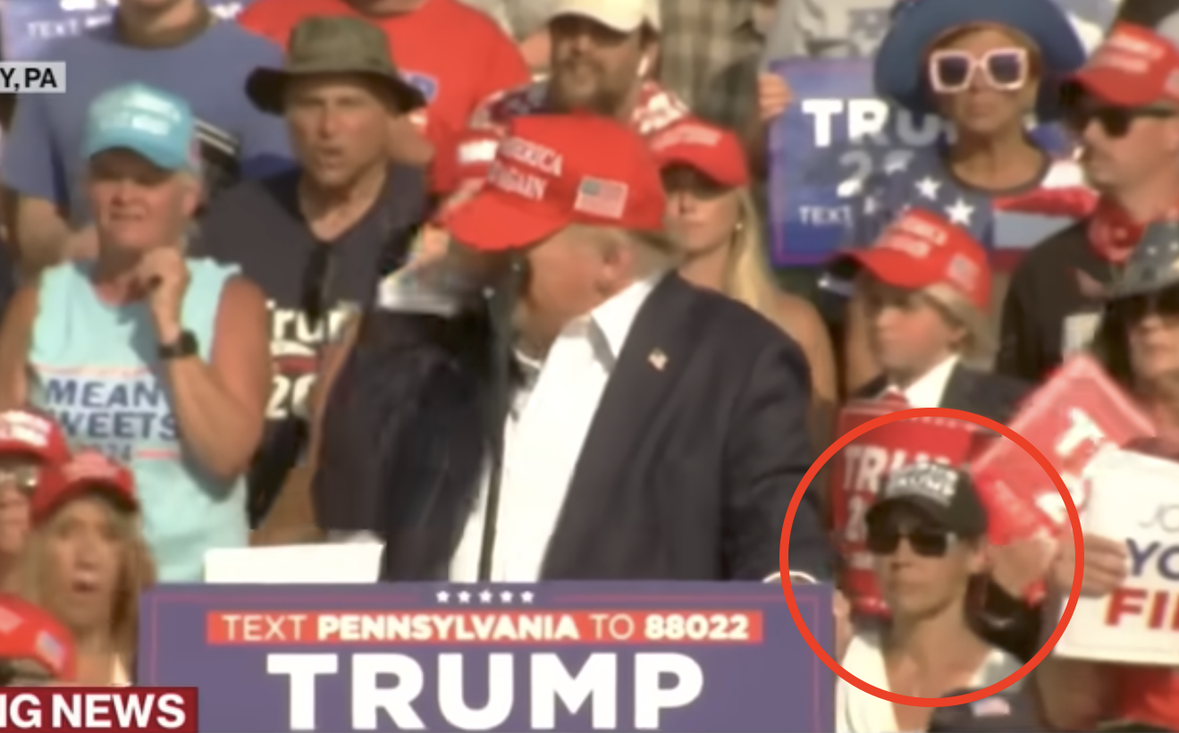 川普遭槍擊時，後方的白衣女子（紅圈處）行為異常，掀起網路熱議。（翻攝ABC新聞畫面）