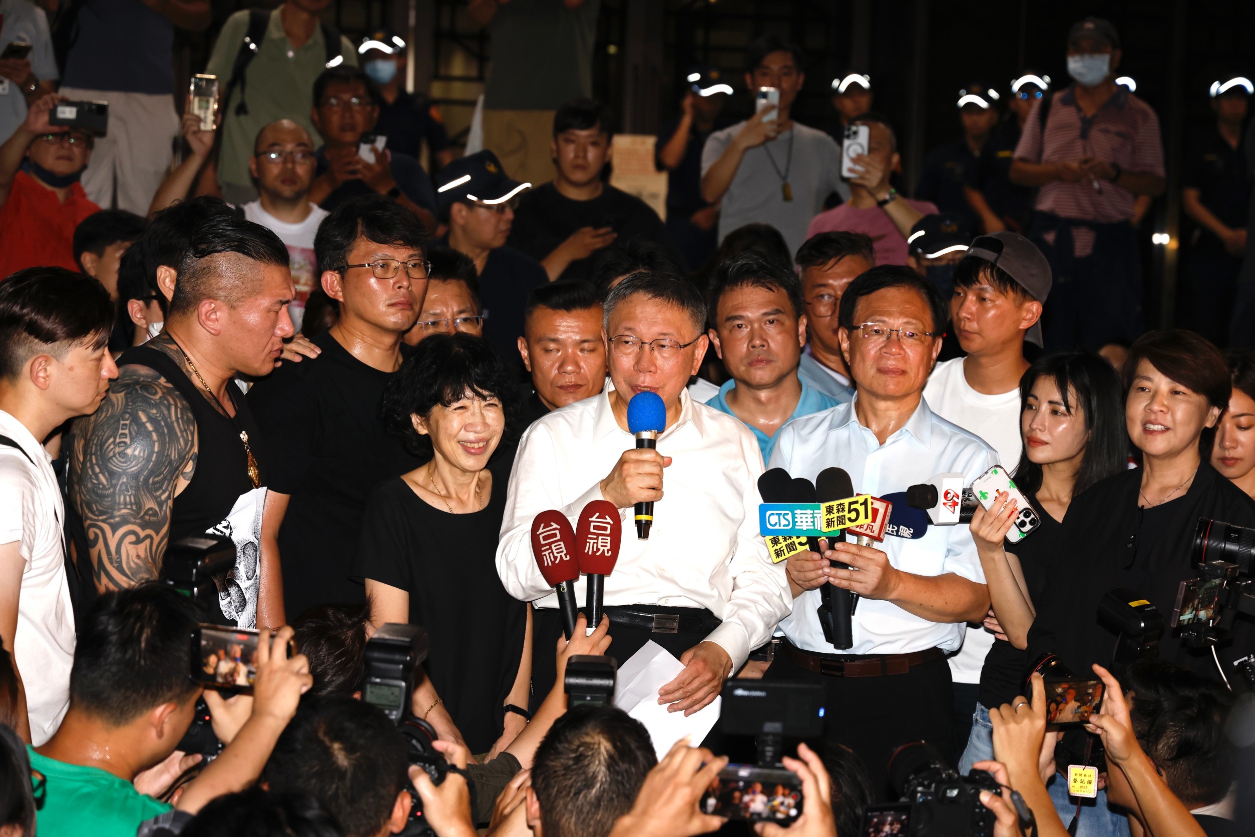 柯文哲（中，握藍色麥克風者）2日凌晨獲無保請回，在支持者擁護下在法院外發表談話。館長陳之漢（左2，黑色背心者）也到場聲援。