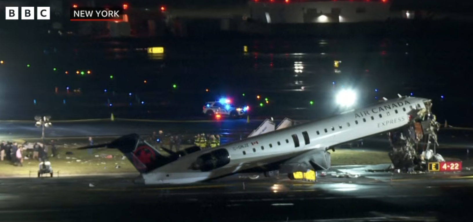 紐約拉瓜迪亞機場事故現場，客機機鼻遭消防車攔腰撞毀，現場殘骸滿地，搜救人員徹夜進行調查。（翻攝自YouTube頻道@BBCNews）