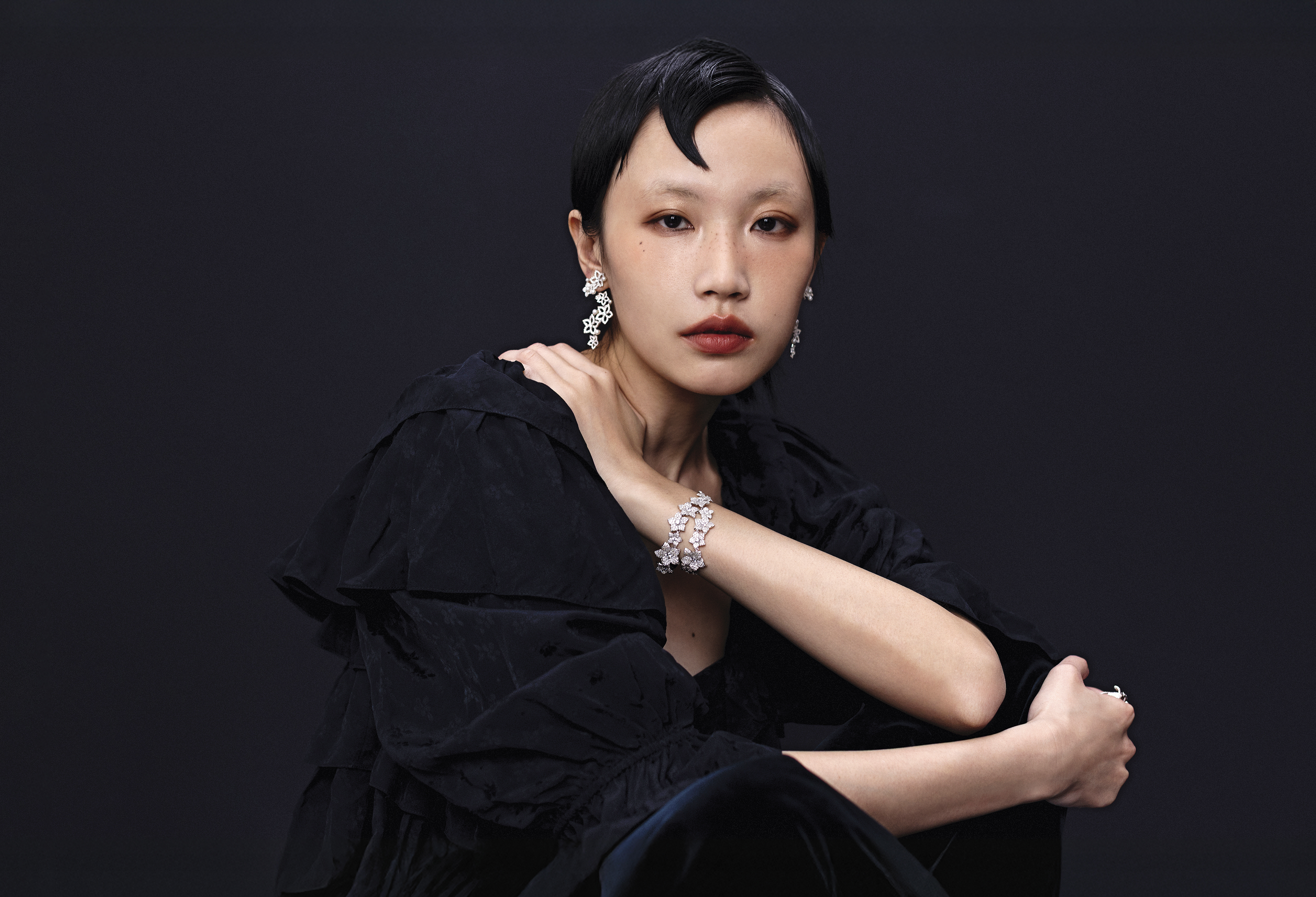  黑色花卉嫘縈荷葉邊短上衣 NT$67,900 by Chloé／夜幕藍天鵝絨喇叭褲 NT$38,000 by Chloé／珍珠花朵吊墜耳釘 NT$10,200 by APM MONACO／個性花朵手鍊 NT$16,900 by APM MONACO／花朵戒指 NT$5,500 by APM MONACO