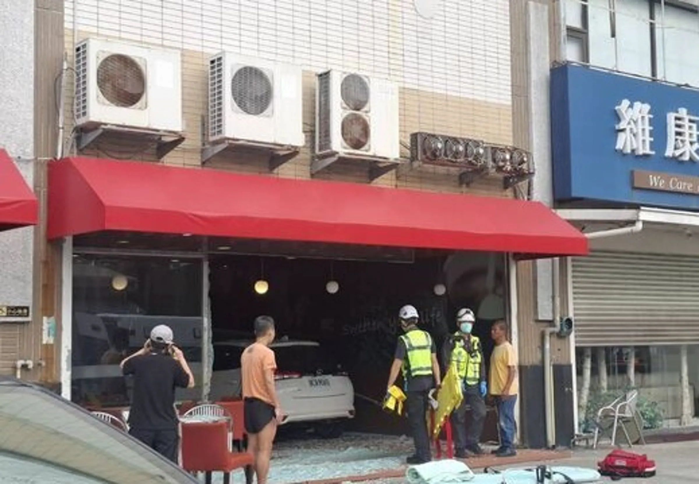 白色轎車撞進85度C咖啡店,造成落地玻璃碎片散落一地,店內桌椅也被撞爛。(翻攝畫面)