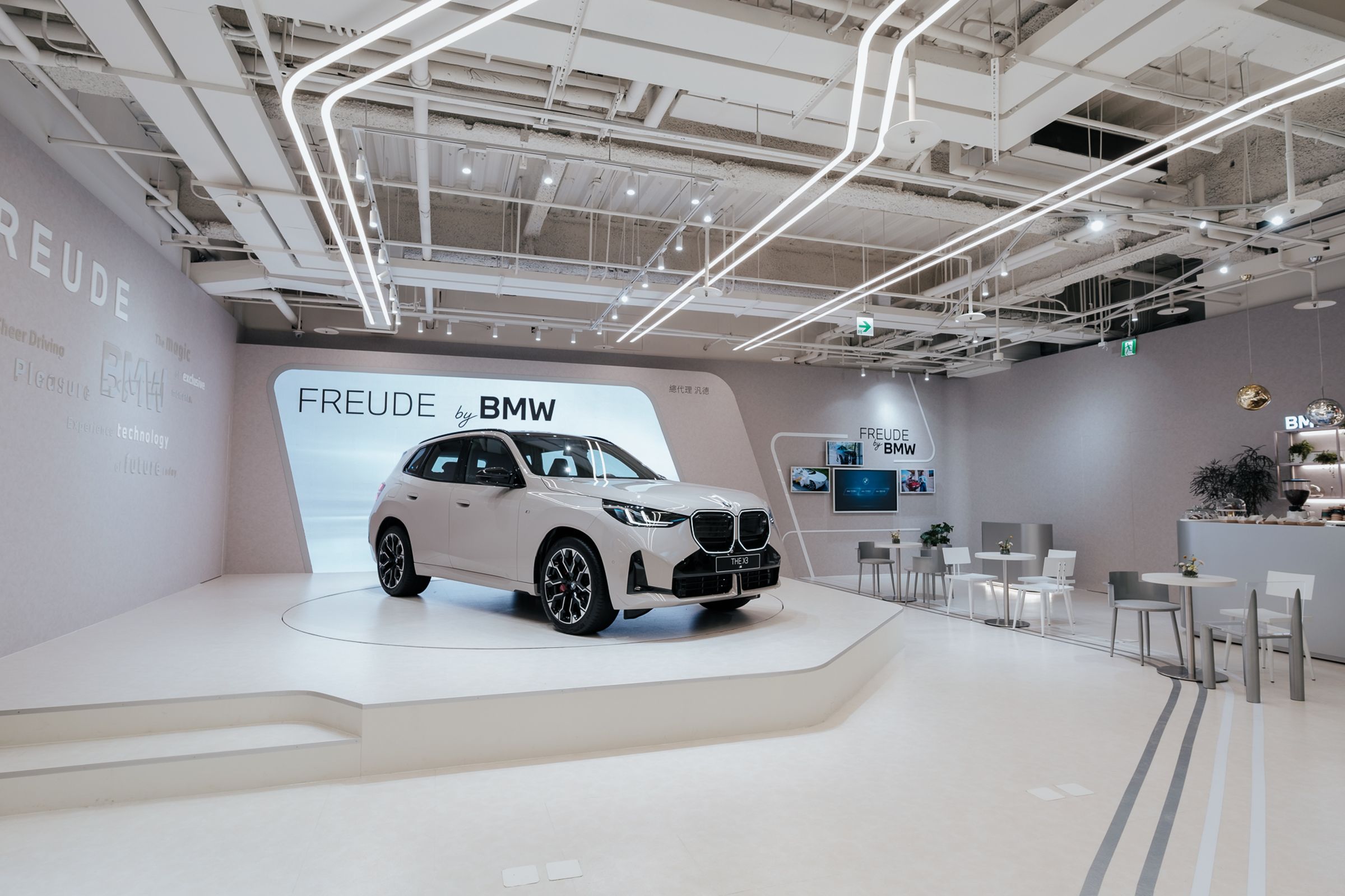  「FREUDE by BMW」品牌概念店以流動的光感線條與極簡設計語彙，一踏入店內，首先映入眼簾的是簡潔俐落且富科技感的設計概念，引領來訪者走入BMW對未來生活與移動方式的嶄新想像。此次展出BMW X3 M50，透過 M Performance 專屬調校，展現動感與舒適兼具的豪華運動休旅風貌