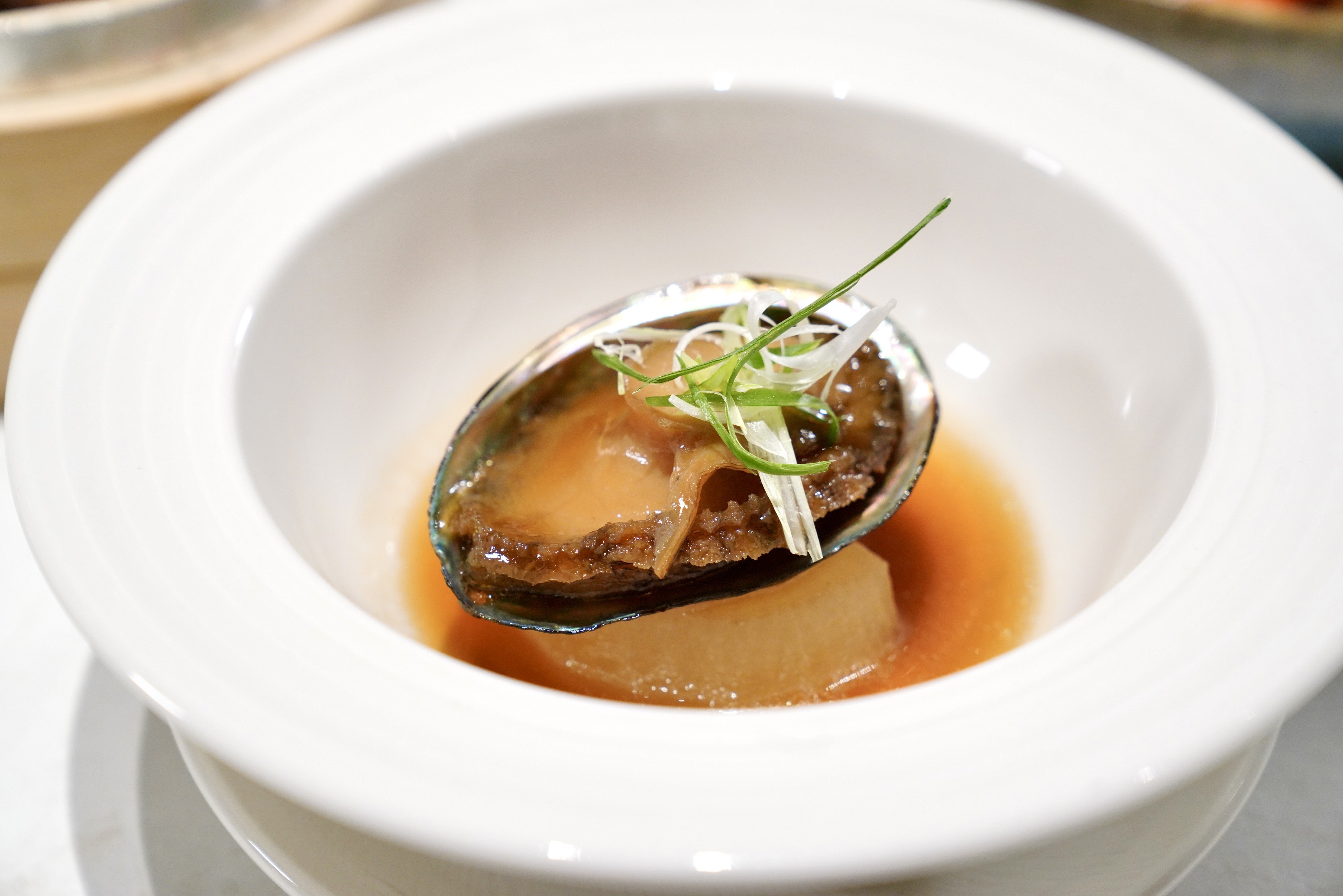 〈鮑魚磯煮白玉〉是以鮮嫩鮑魚佐慢燉白蘿蔔，鹹香細膩、風味層次豐富。（攝影組）
