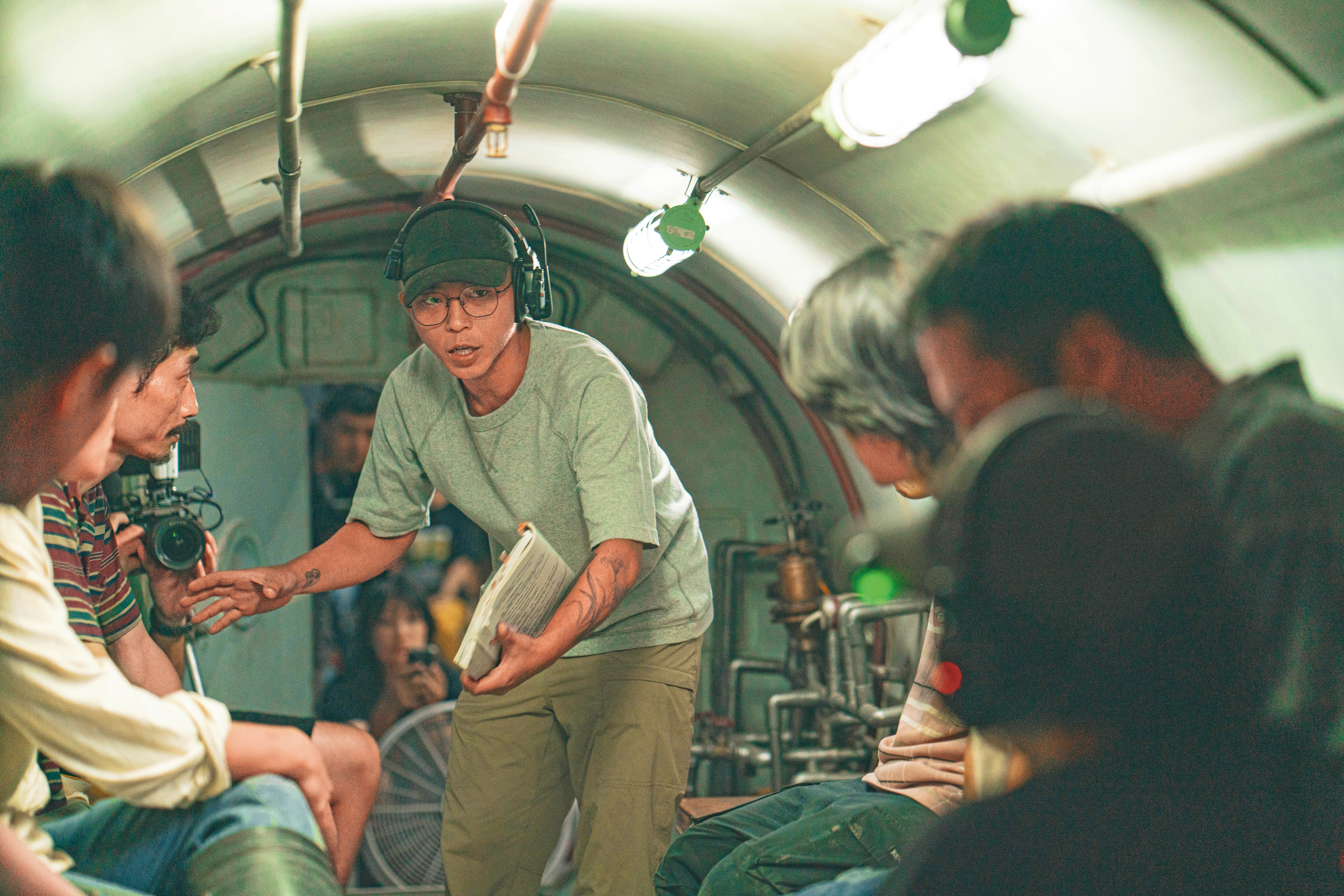 導演朱平（中）在隧道工人減壓用的壓力艙大型道具內部與演員們討論。（客家電視台提供）