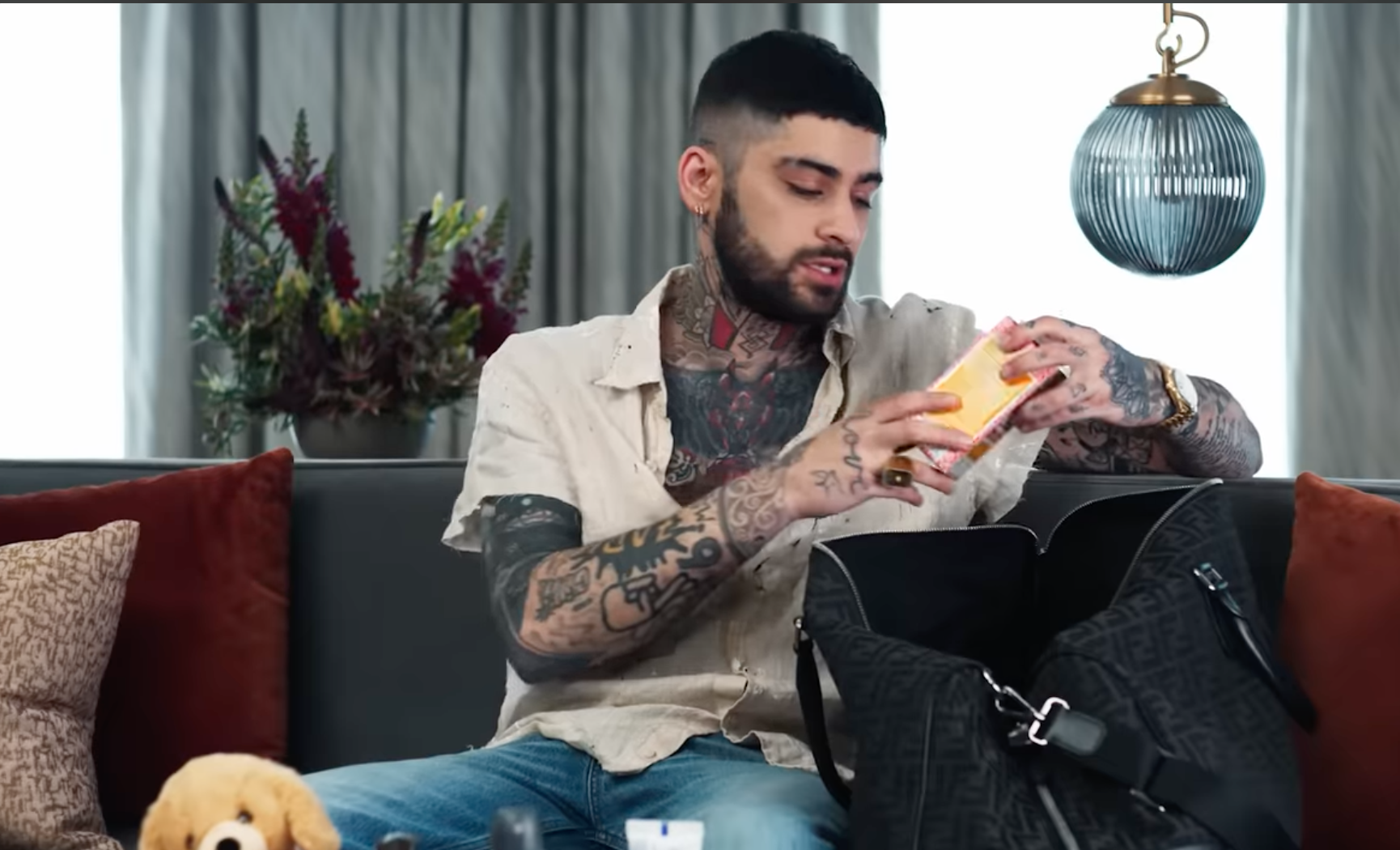 英國歌手贊恩打開包包，介紹隨身必備的小物，結果拿出一個很熟悉的紙盒。（翻攝自British Vogue官方YouTube）