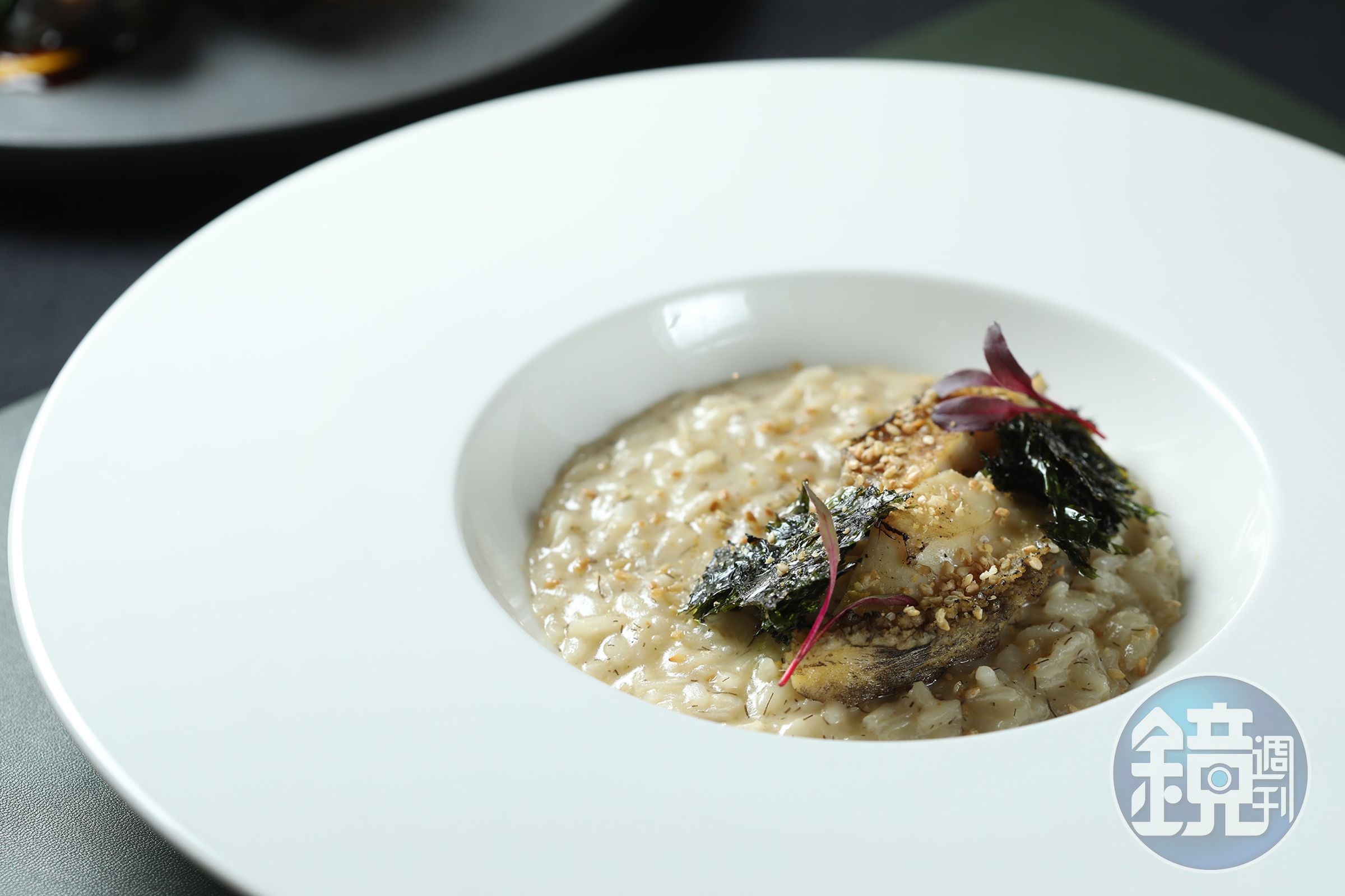 「鮑魚、義大利燉飯」將鮑魚搭配髮菜與紫菜，並以芝麻香氣畫龍點睛，創造層次豐富的海洋燉飯體驗。（1,780元／套餐菜色）