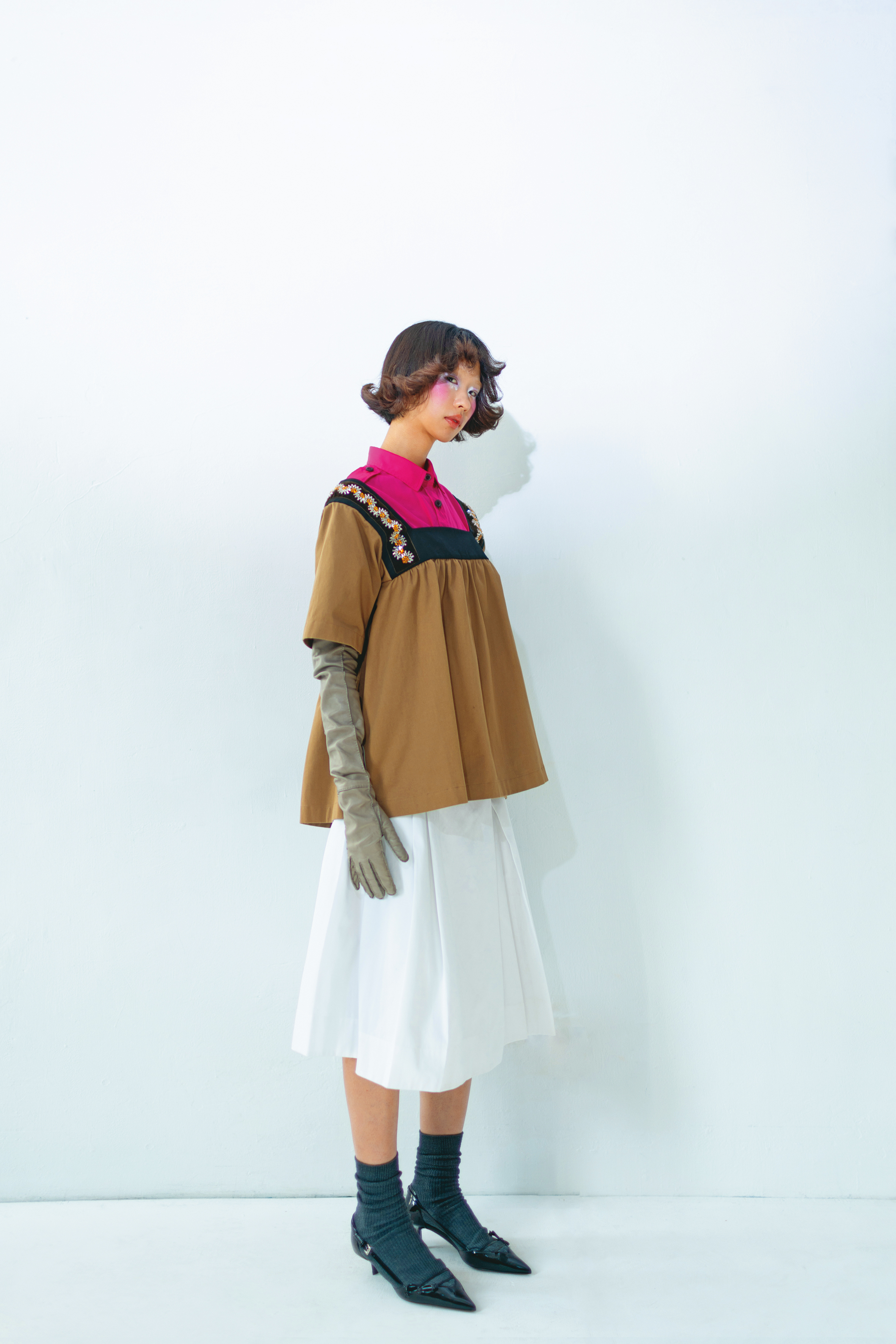 刺繡背心上衣 價格店洽／桃粉色襯衫 價格店洽／白色打褶過膝裙 價格店洽／黑色尖頭低跟鞋 價格店洽／灰色長版手套 價格店洽／All by PRADA